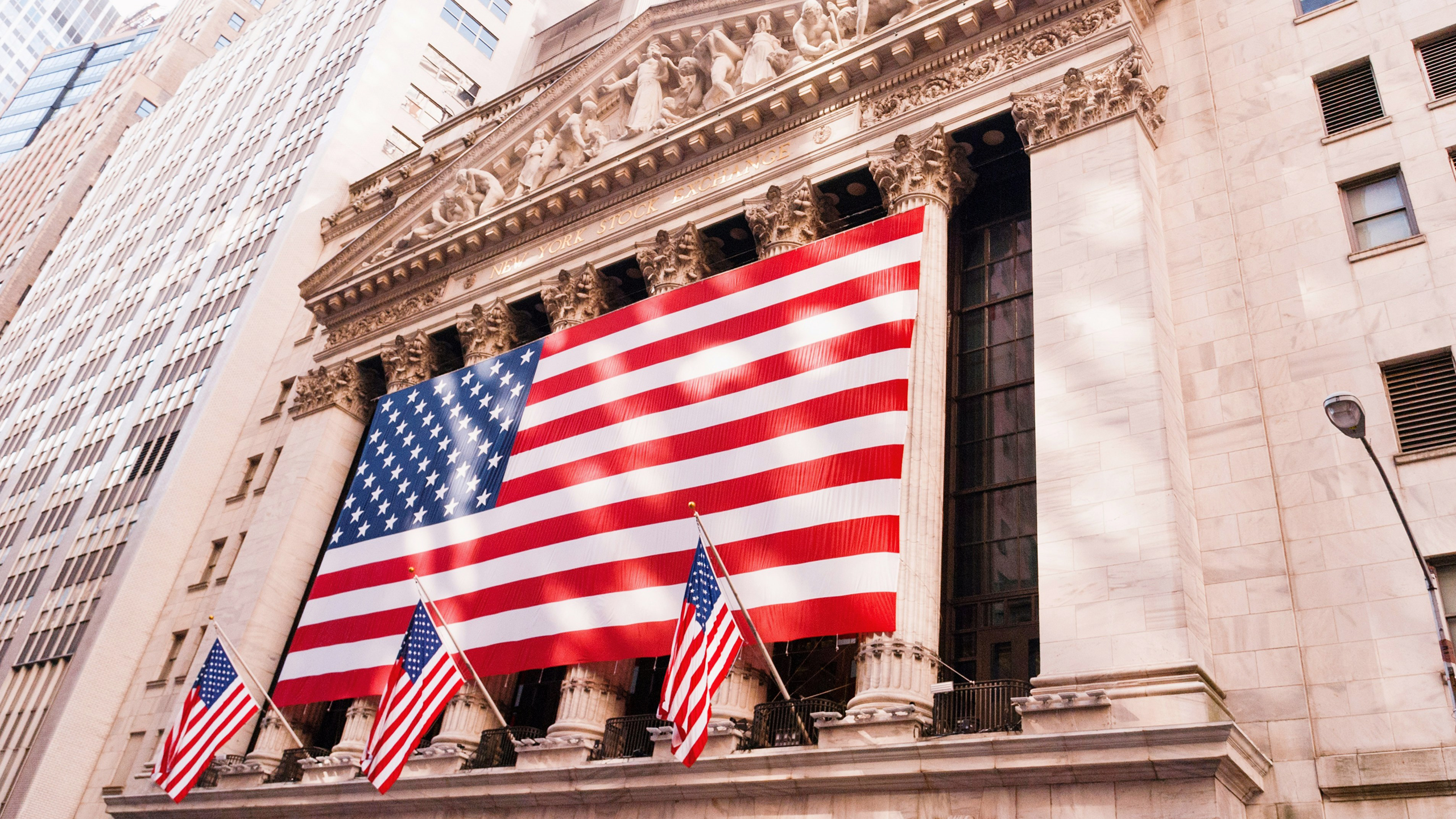 Photo of U.S. flags hanging from New York Stock Exchange building