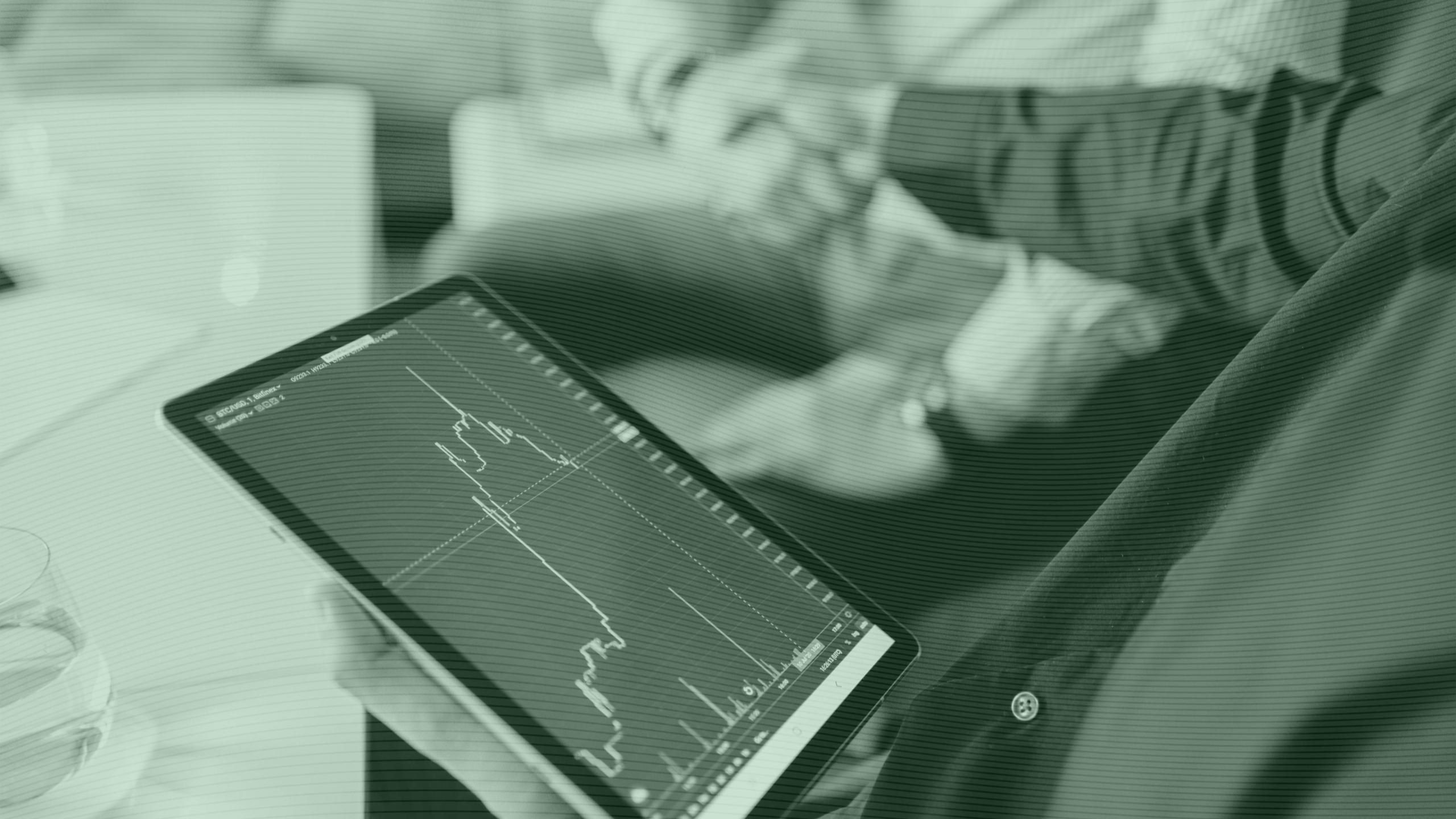 Photo of two people shaking hands and looking at a tablet with a stock chart on it