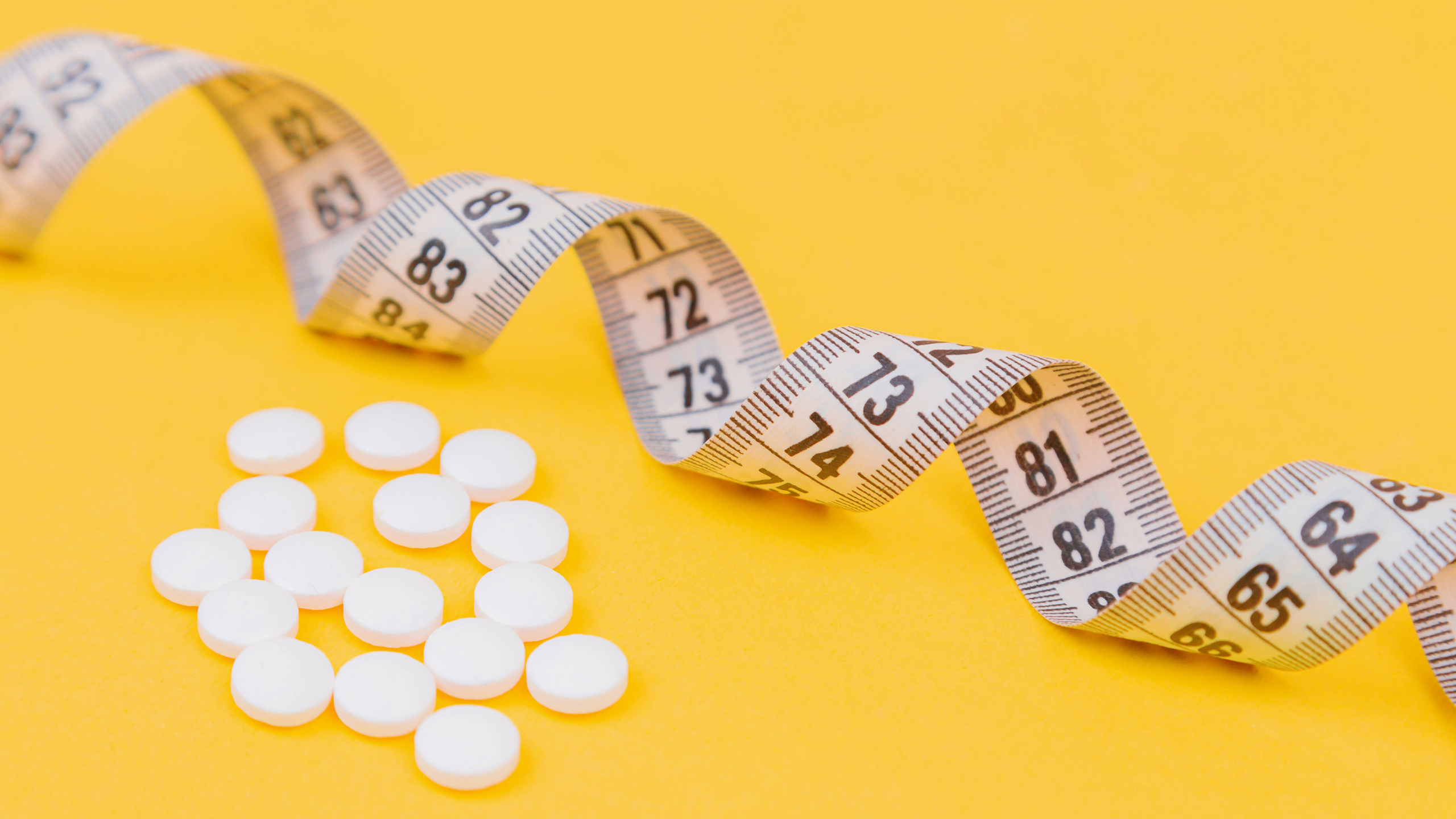 Photo of a tape measure and obesity pills
