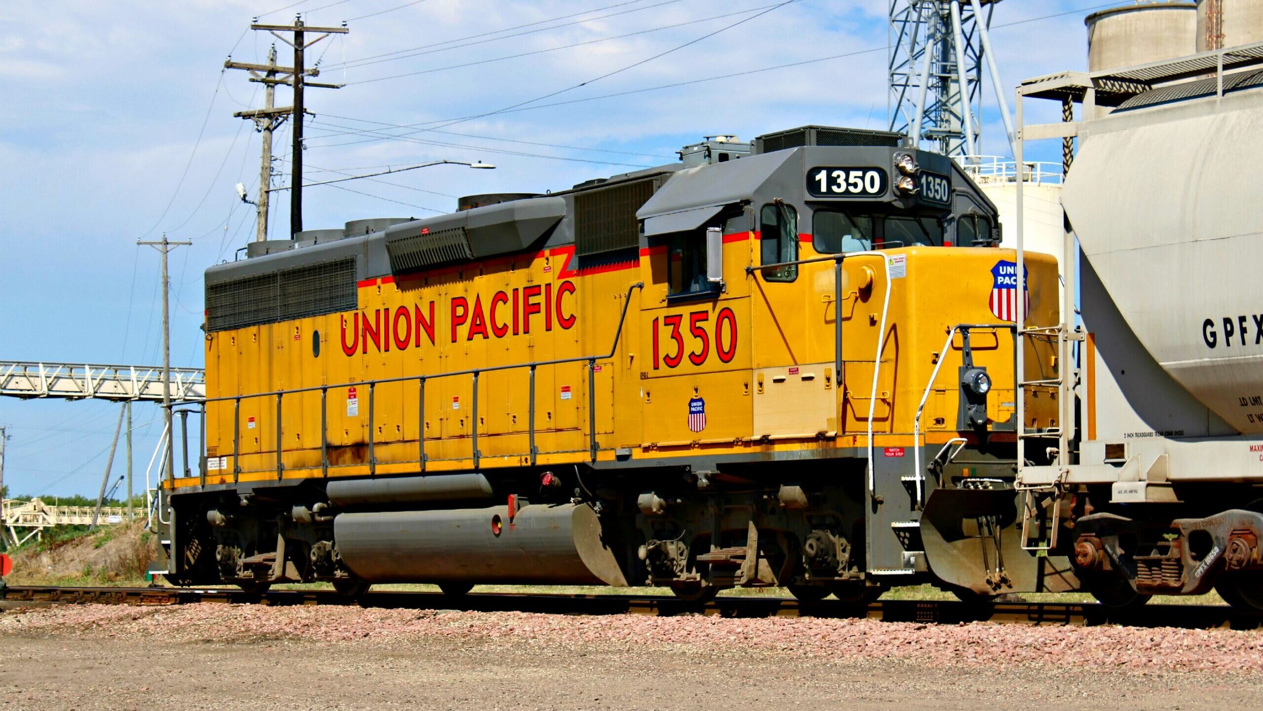 A Union Pacific engine car is stationary on a railway track in front of an industrial site.