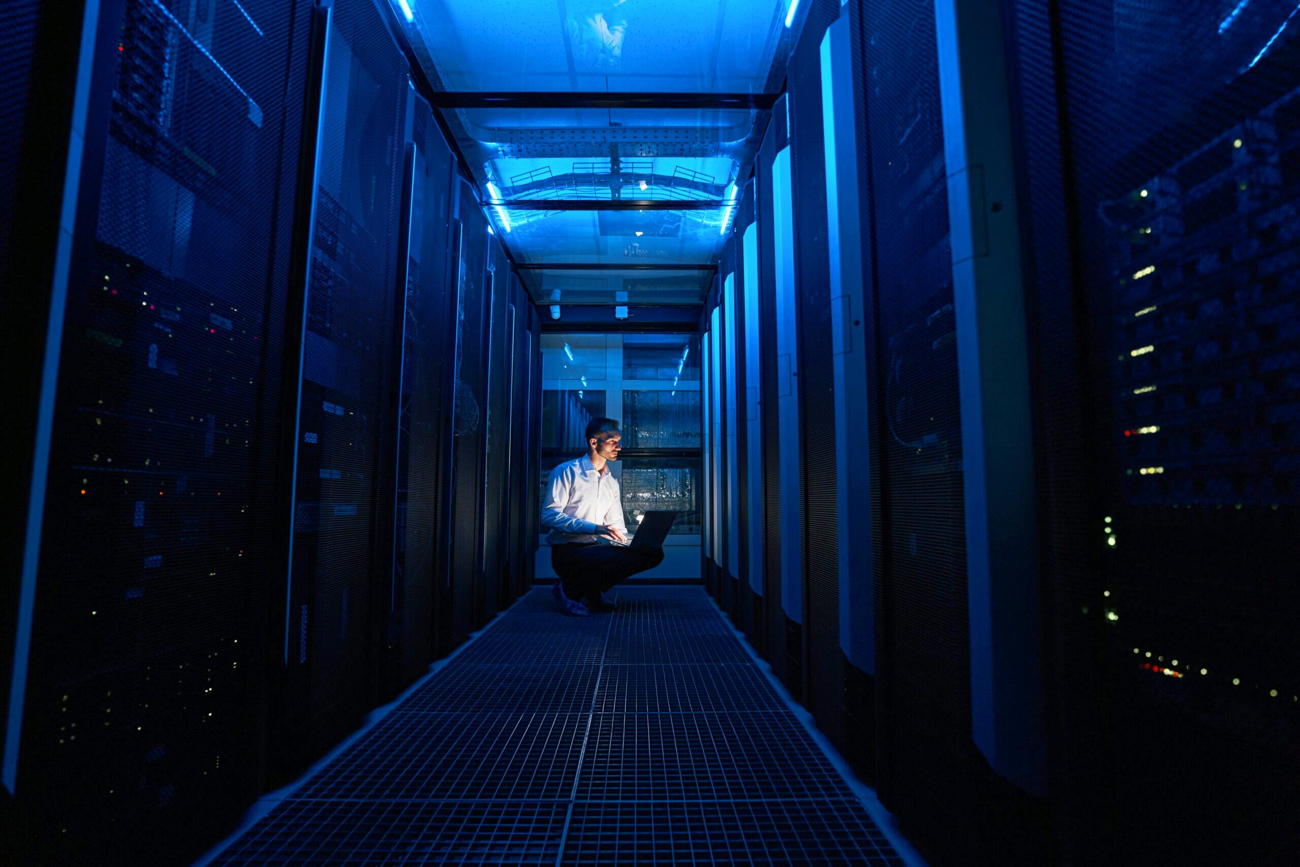 Person on a computer amid server racks.