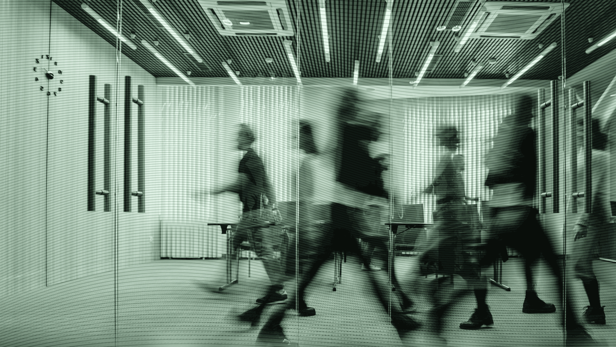Blurry people walking in an office building.