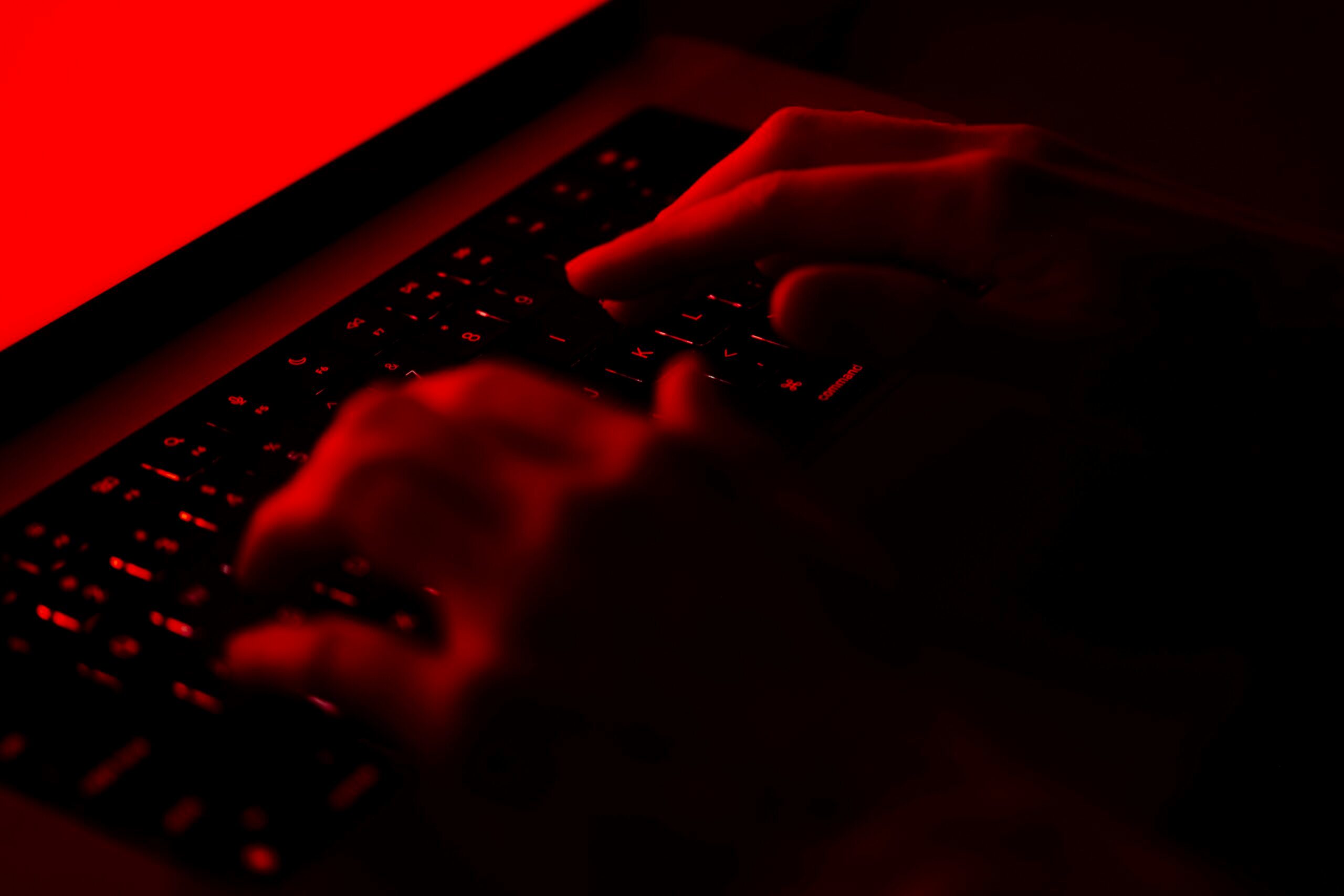 Photo of hands on a keyboard in red light.