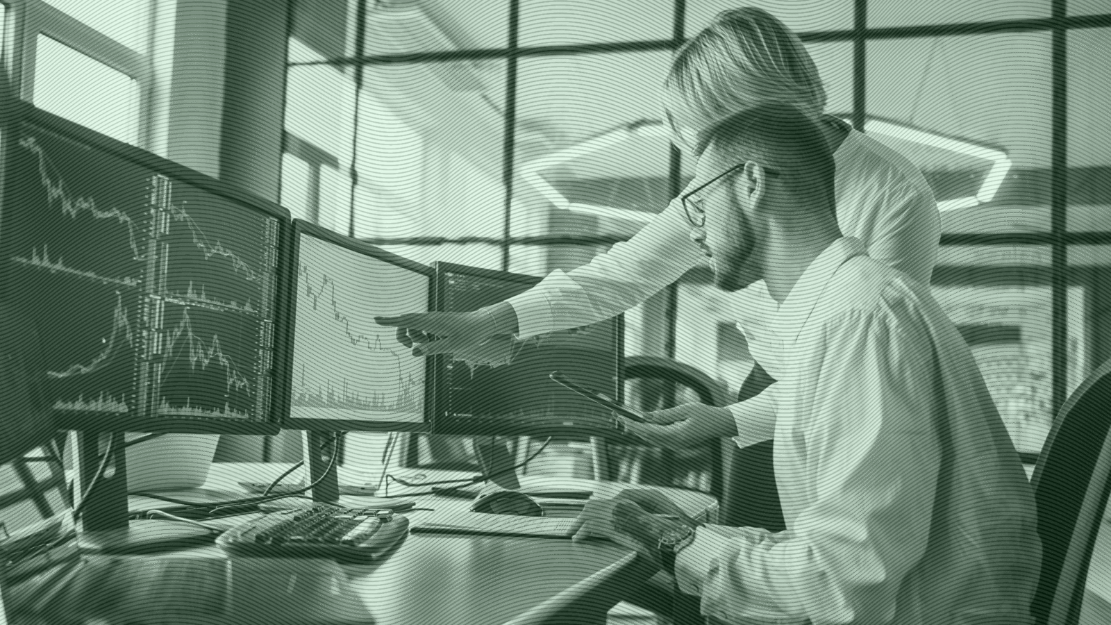 Photo of two people looking at monitors with stock charts