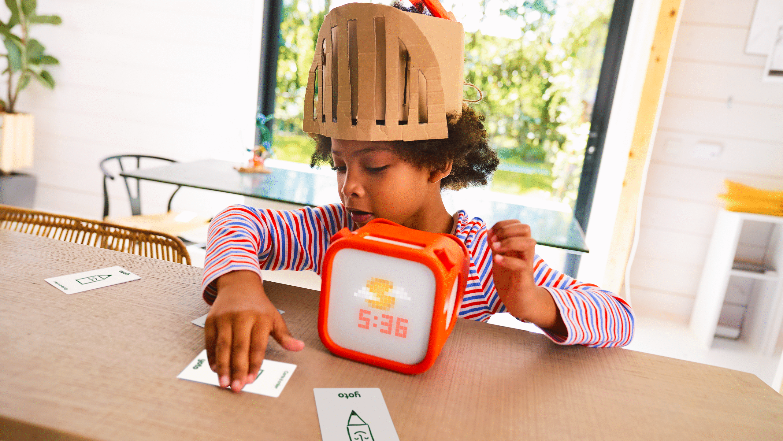 A child plays with a Yoto speaker on a table at home.