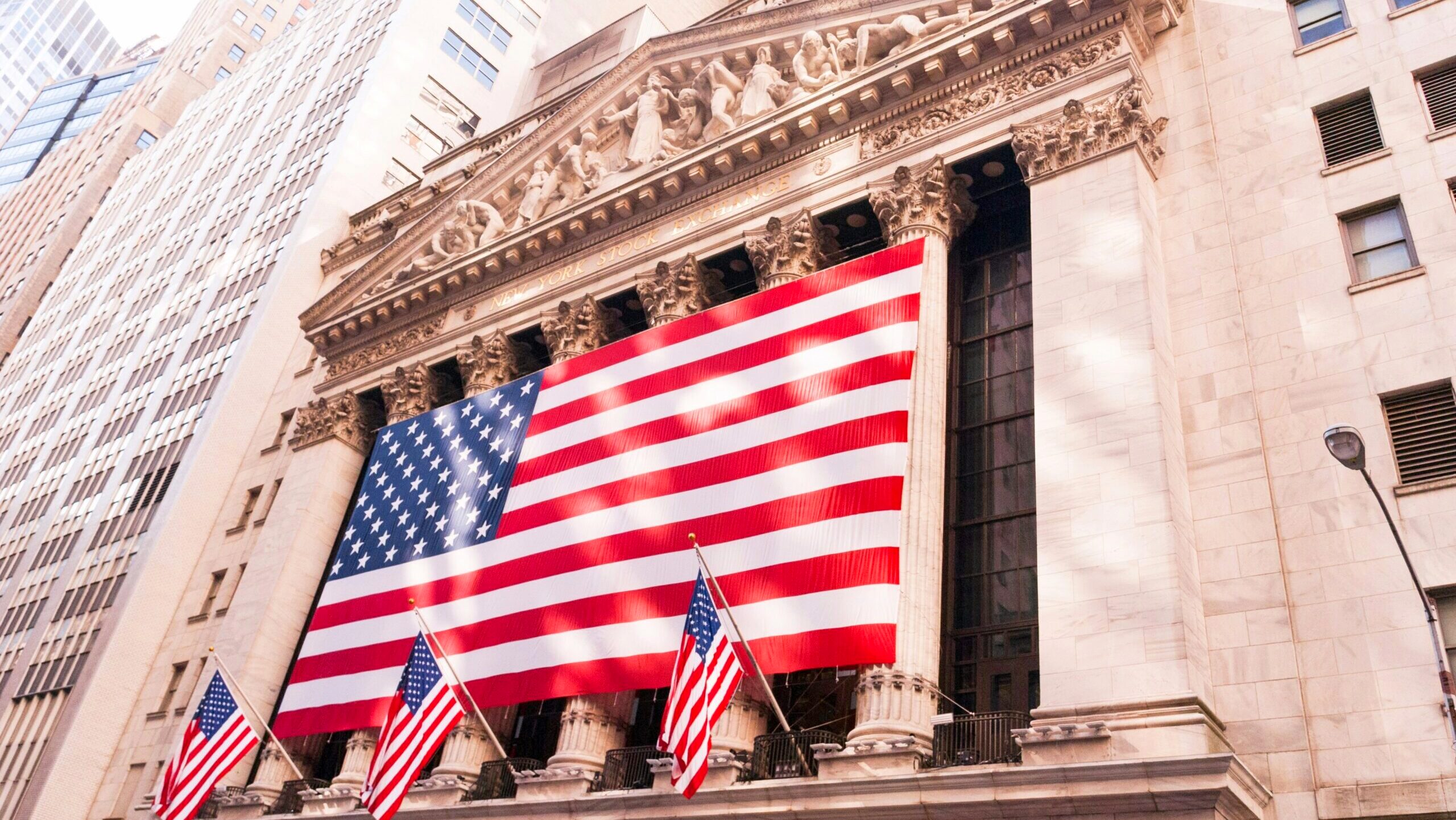 A large American flag hangs in front of the New York Stock Exchange in New York City.