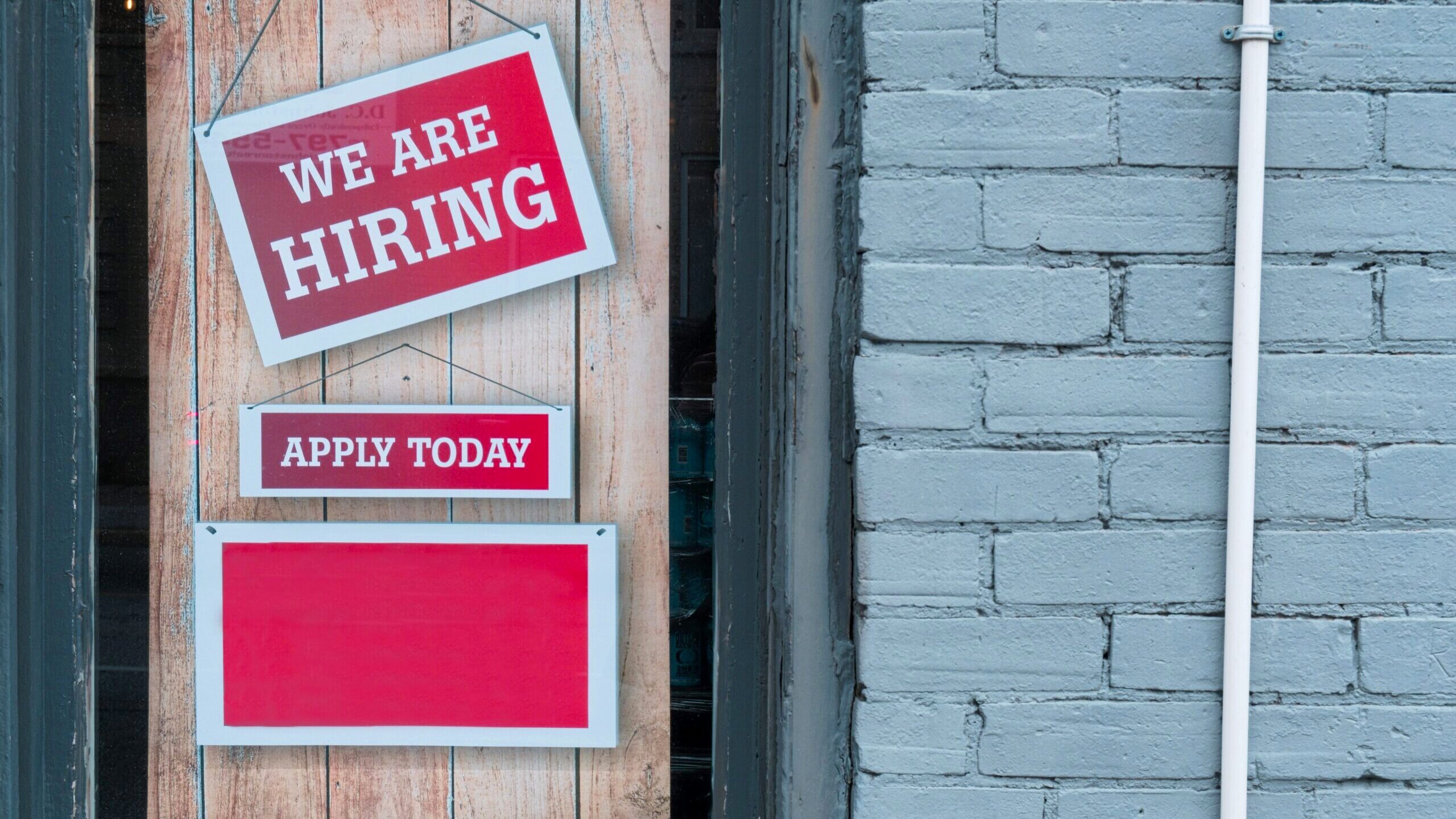 A sign in a door says "We are Hiring."