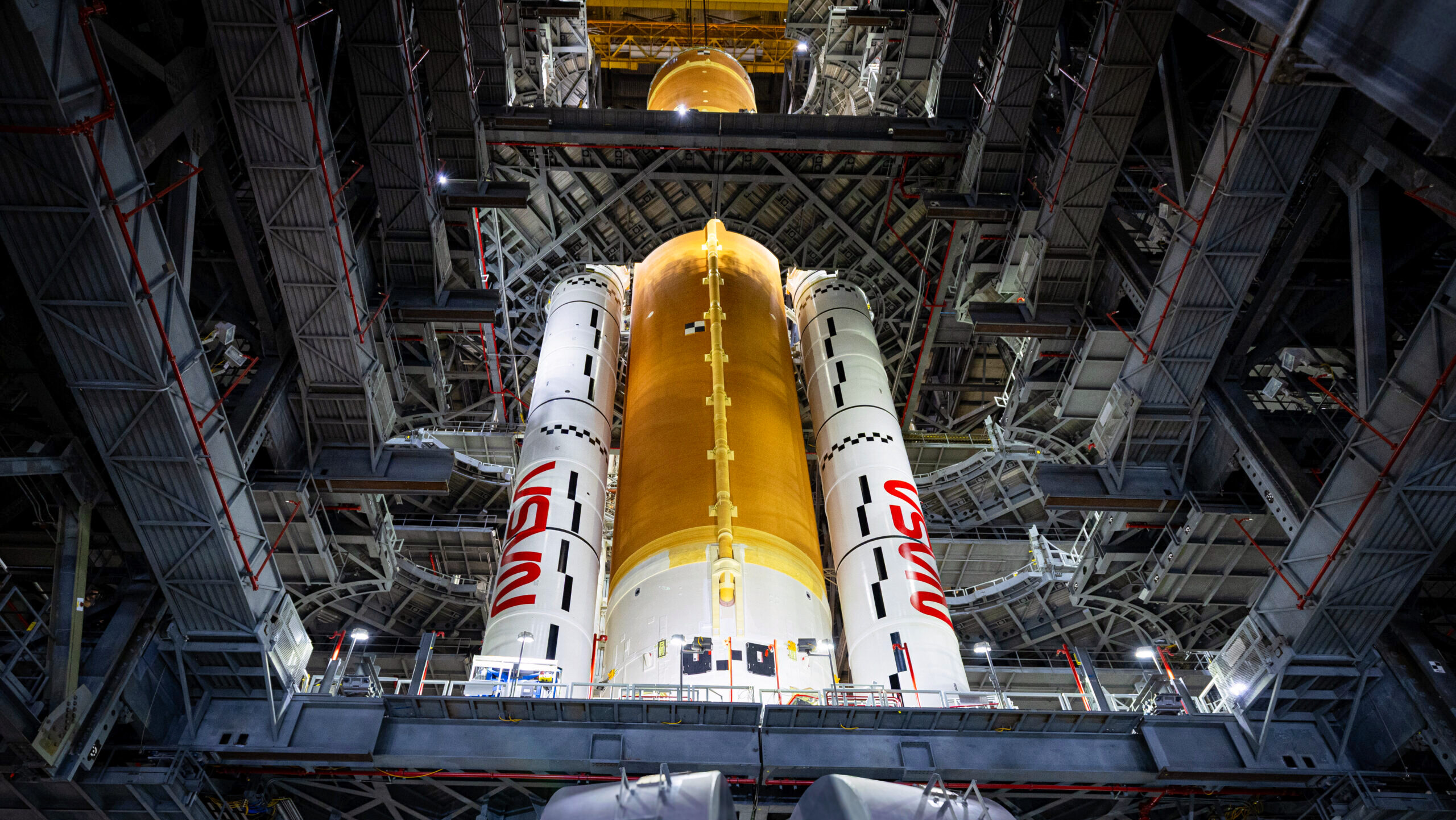 A Space Launch System Moon rocket with solid rocket boosters is shown in the bay of an assembly building at NASA's Kennedy Space Center.
