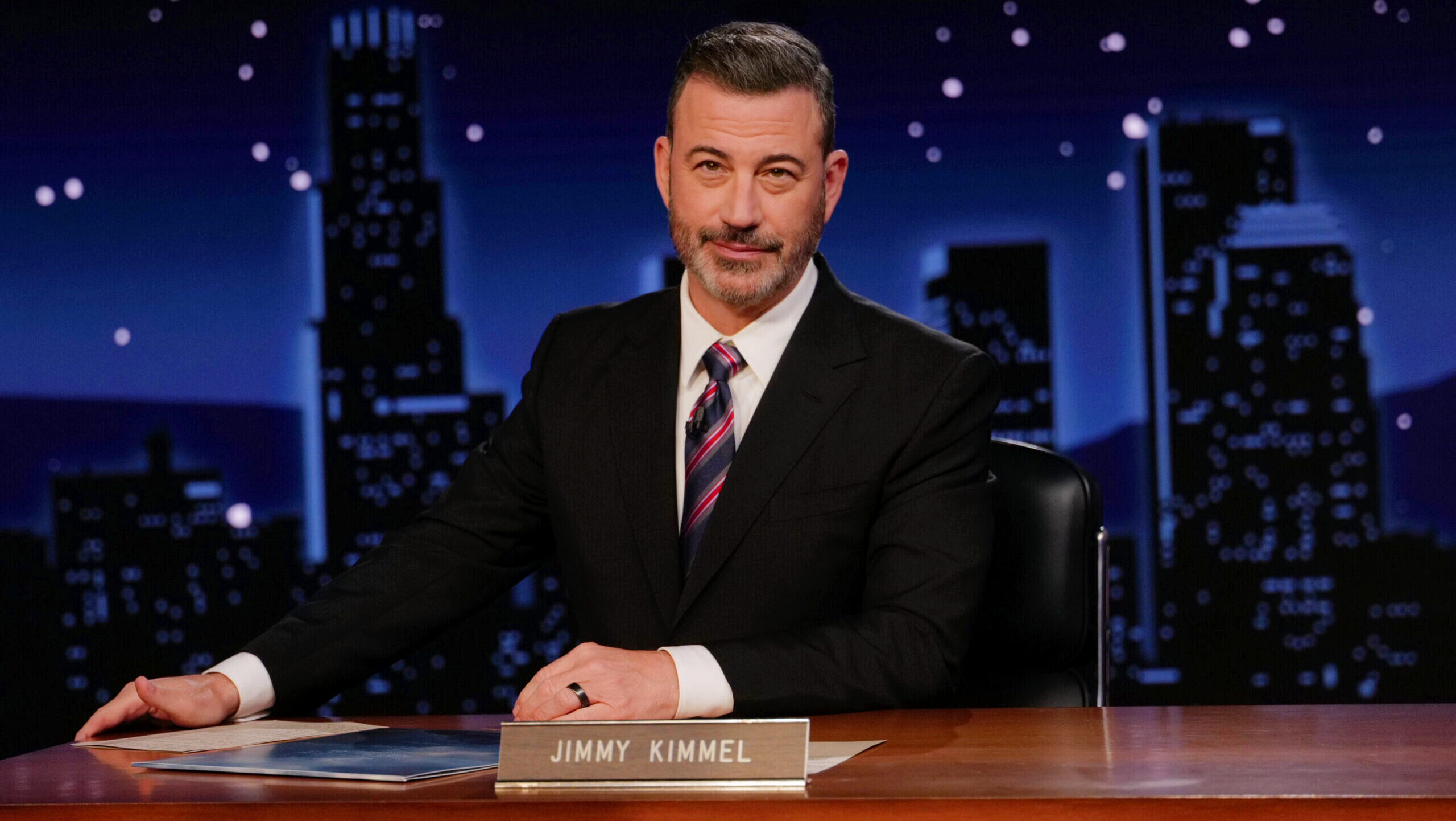 Jimmy Kimmel Live host Jimmy Kimmel is shown seated at his desk on the set of the show.