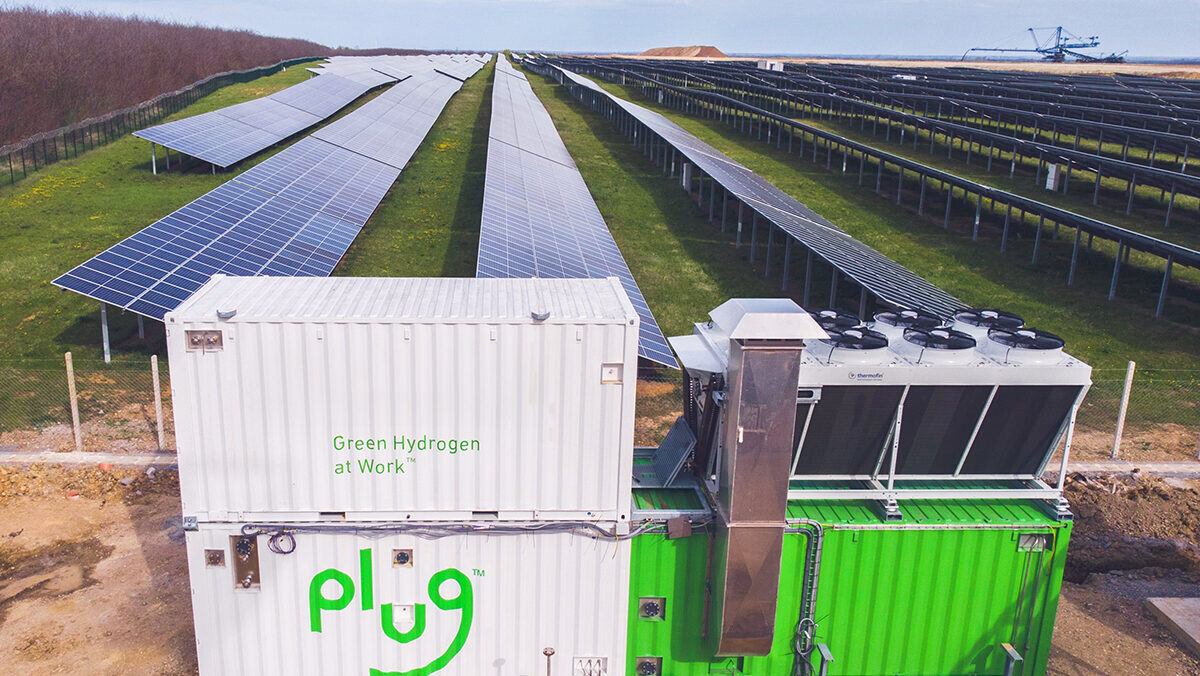 A Plug Power electrolyzer system is shown in front of a field of solar panels.