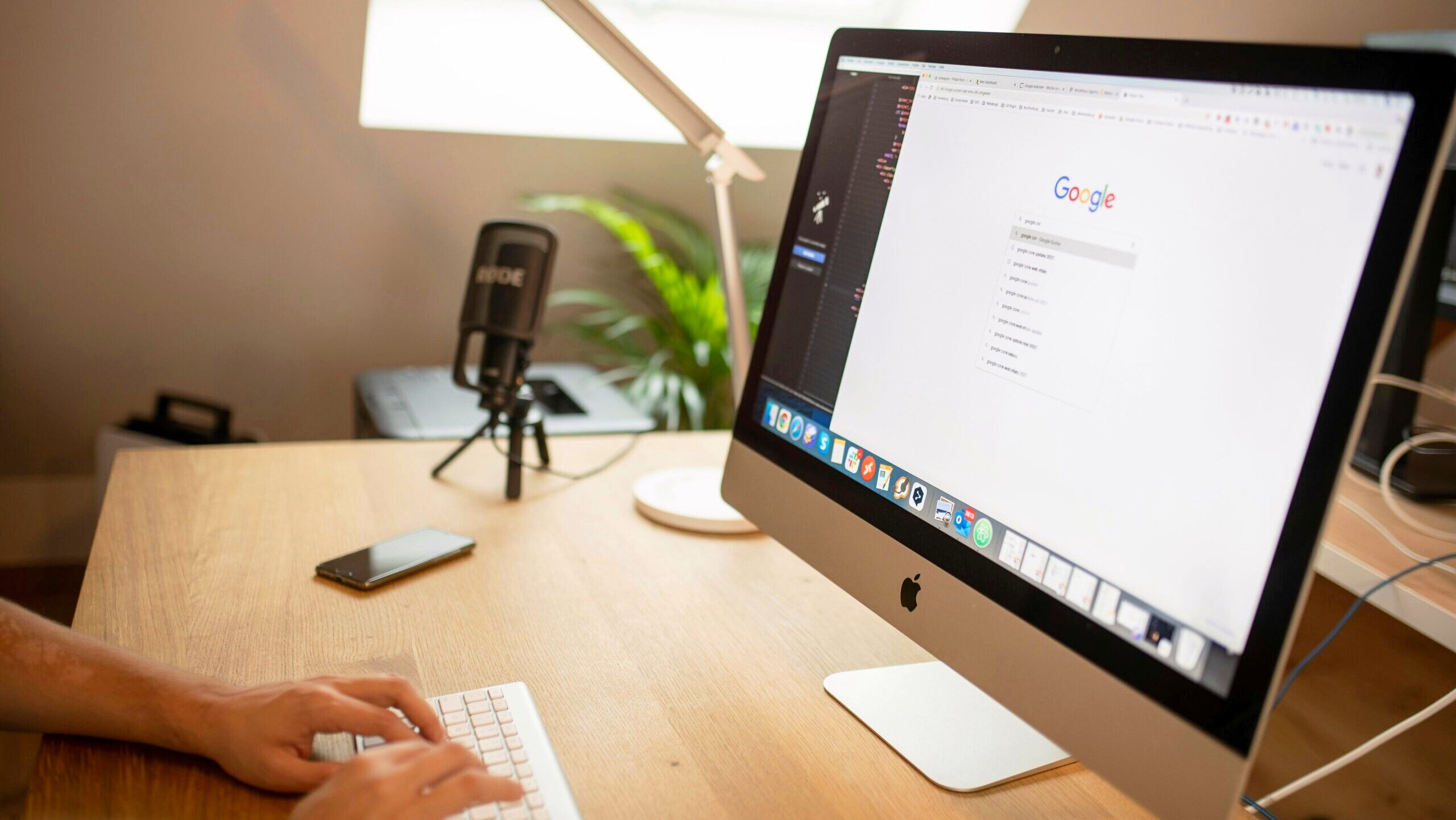 A person performs a Google search on an Apple Mac desktop computer.