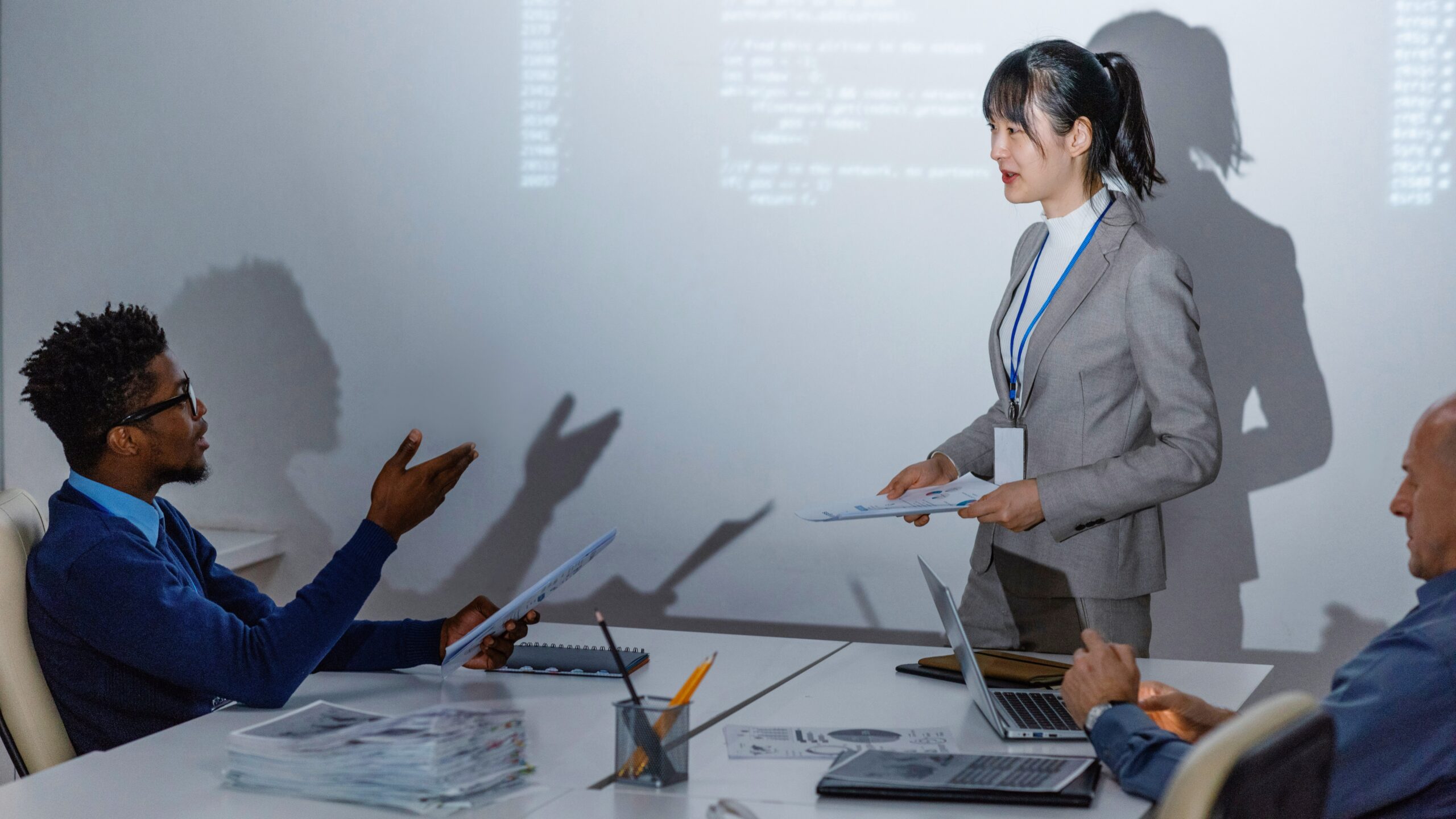 Photo of two business people talking with code in the background