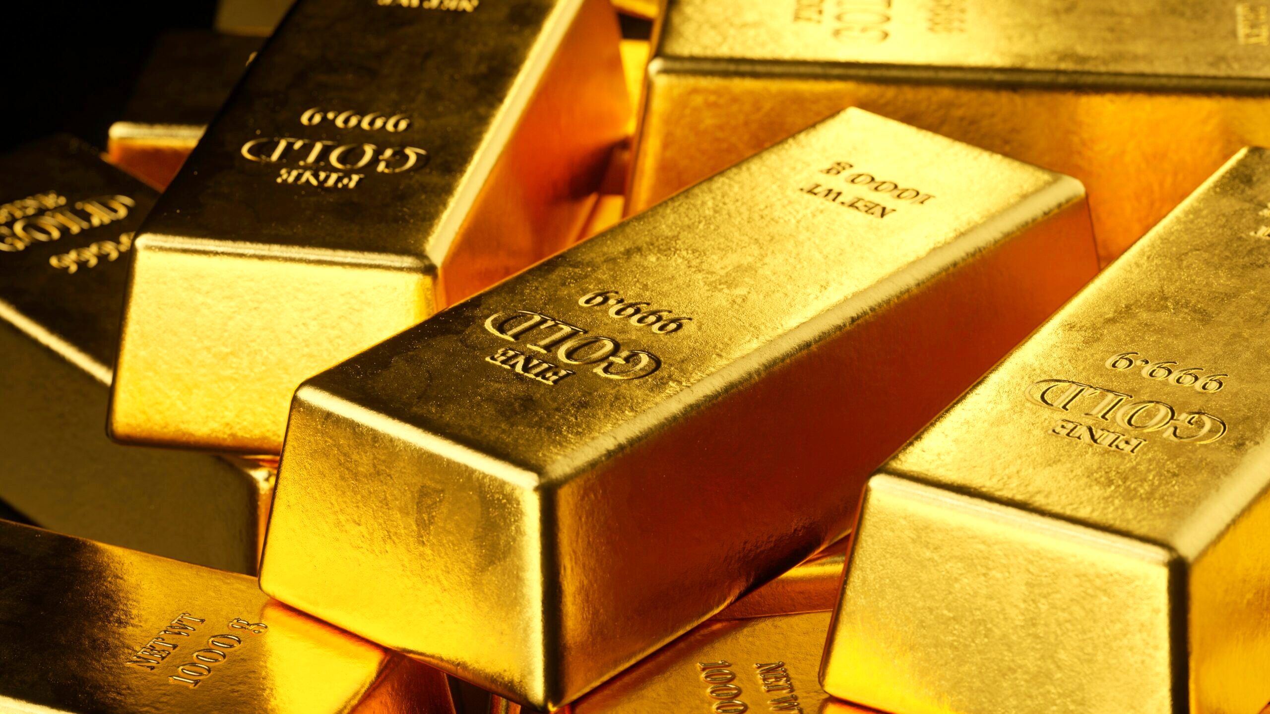 A series of stacked gold bars are shown up close.