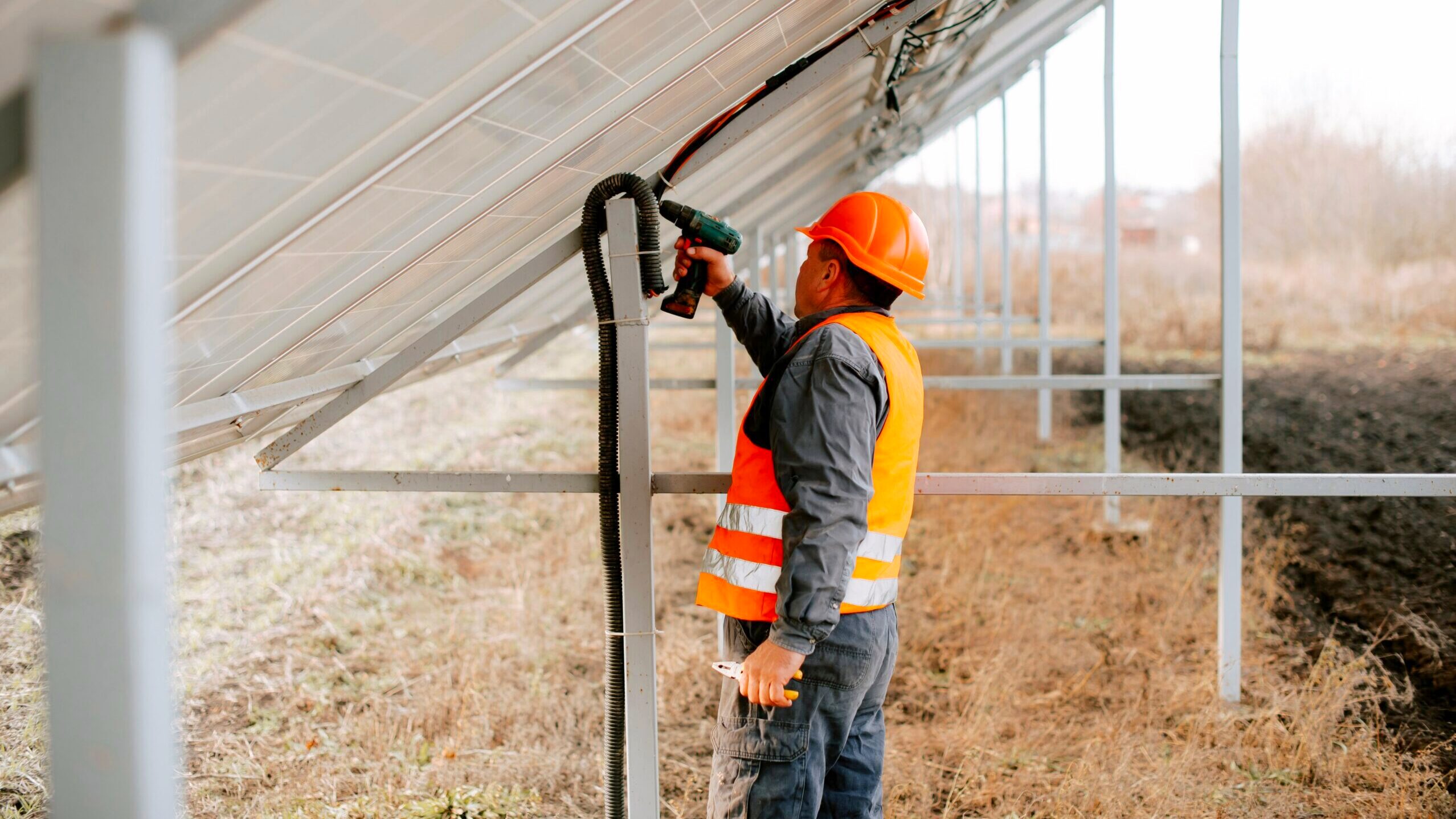 A worker is seen using a power drill to install a solar panel.