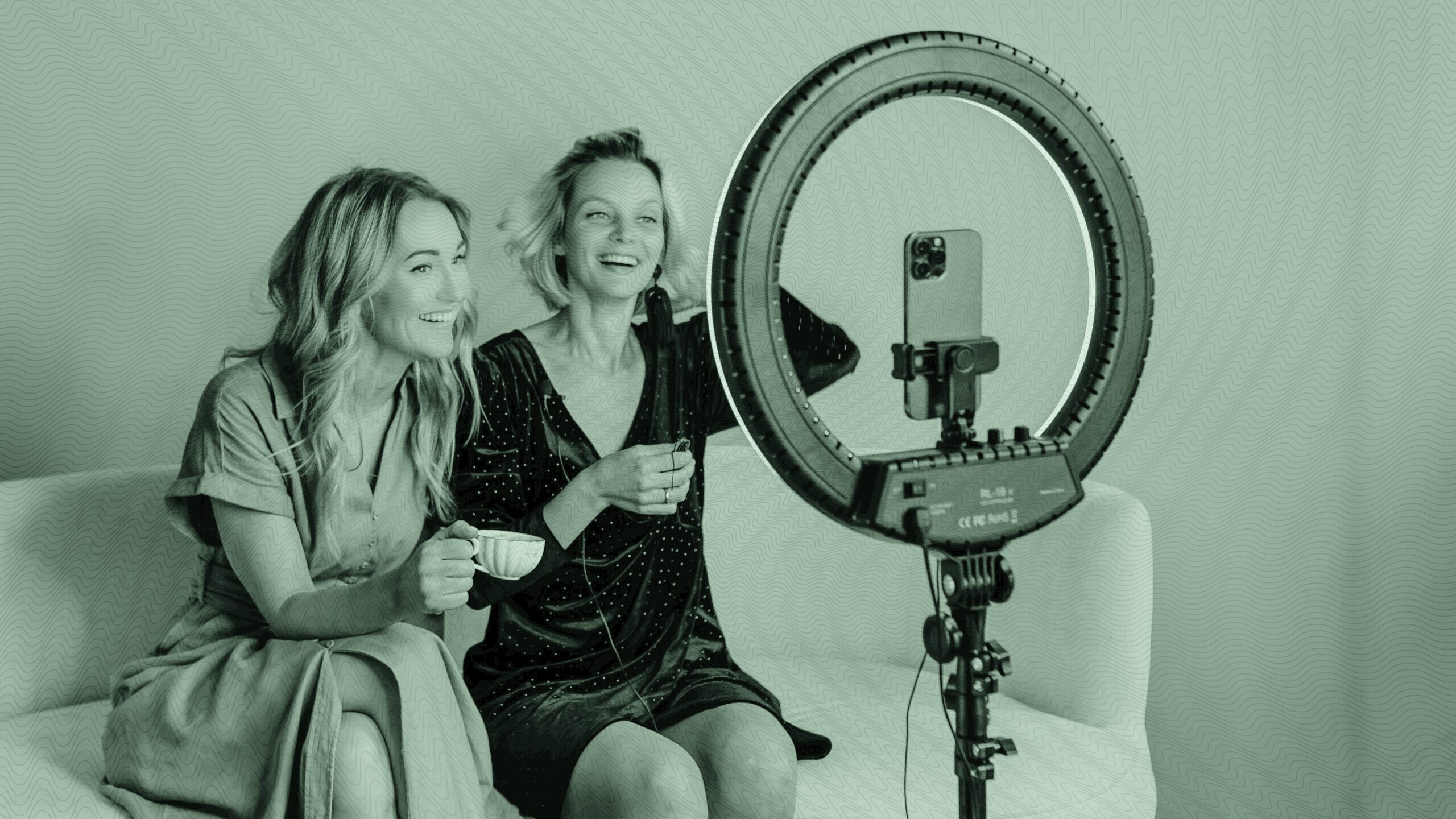 two women recording a video on their phone.