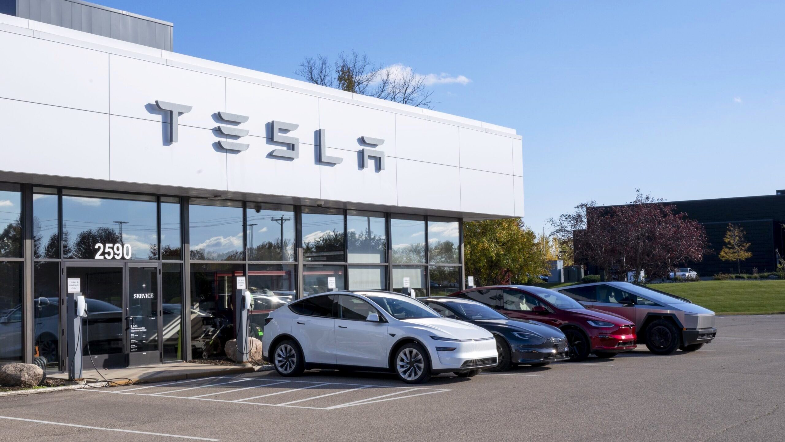 A Tesla dealership in Maplewood, Minnesota with various models of the company's electric vehicles displayed outside is shown on a sunny day.