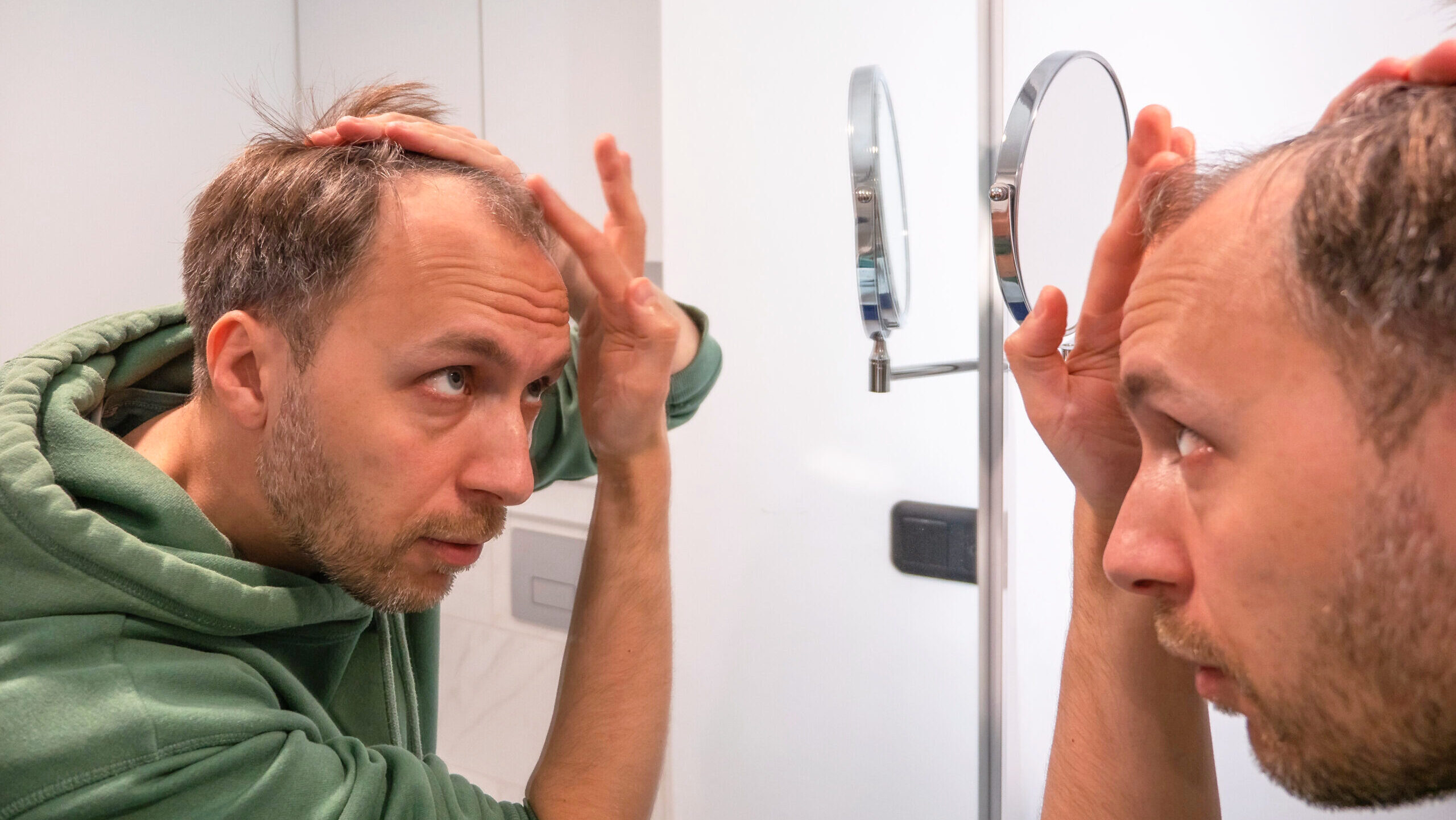 Photo of a balding man looking in the mirror.