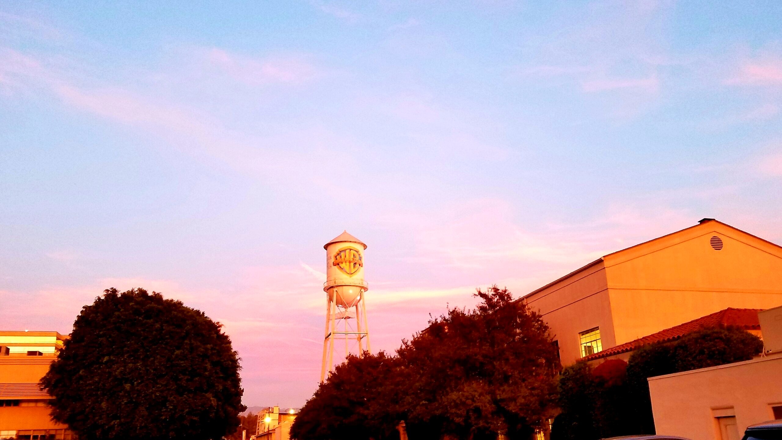 The Warner Bros. Water Tower at Warner Bros. Studios in Burbank, California is seen set against a pink sunset sky.