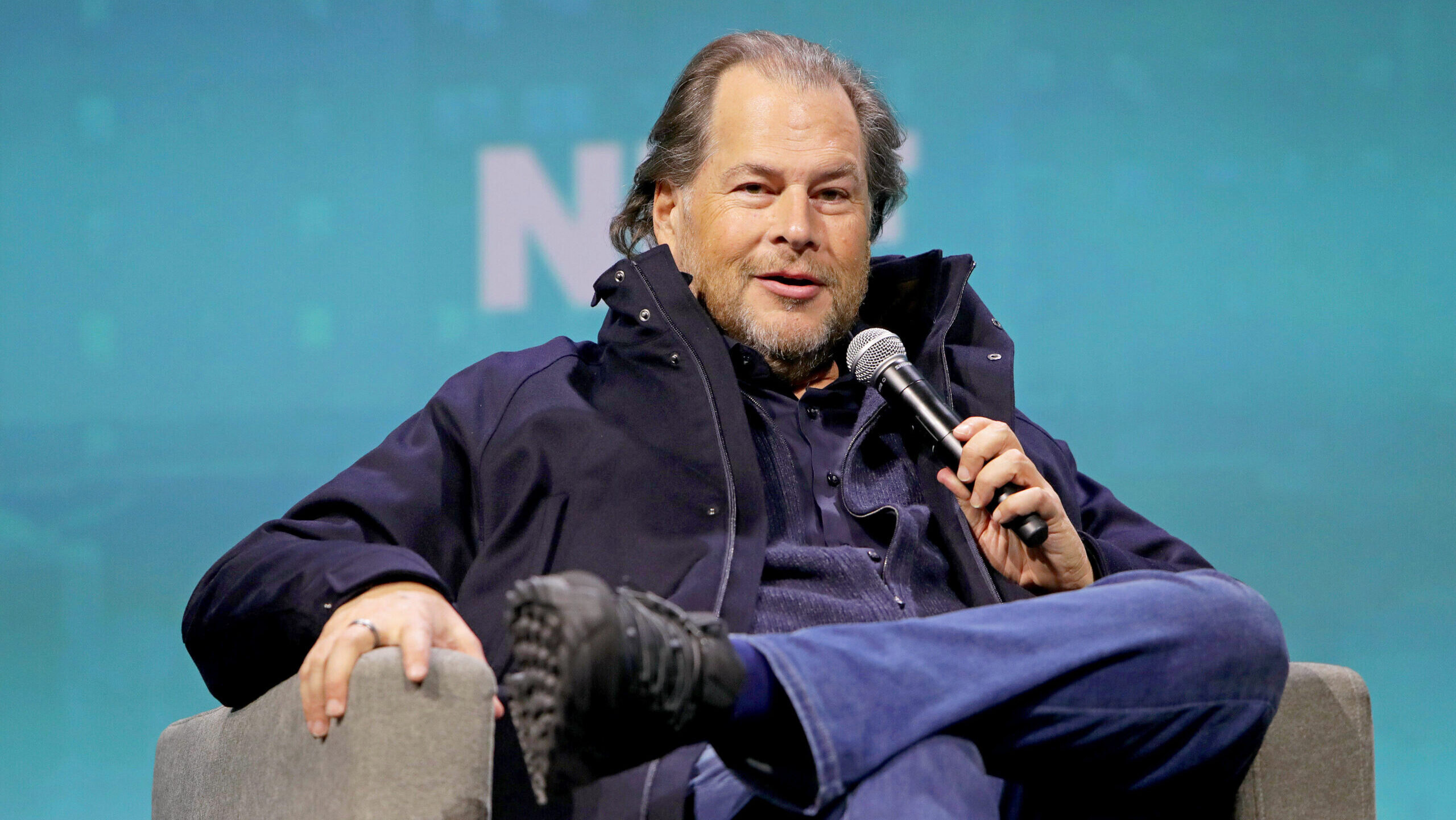 Salesforce CEO Marc Benioff addresses the National Retail Federation while seated in a chair.