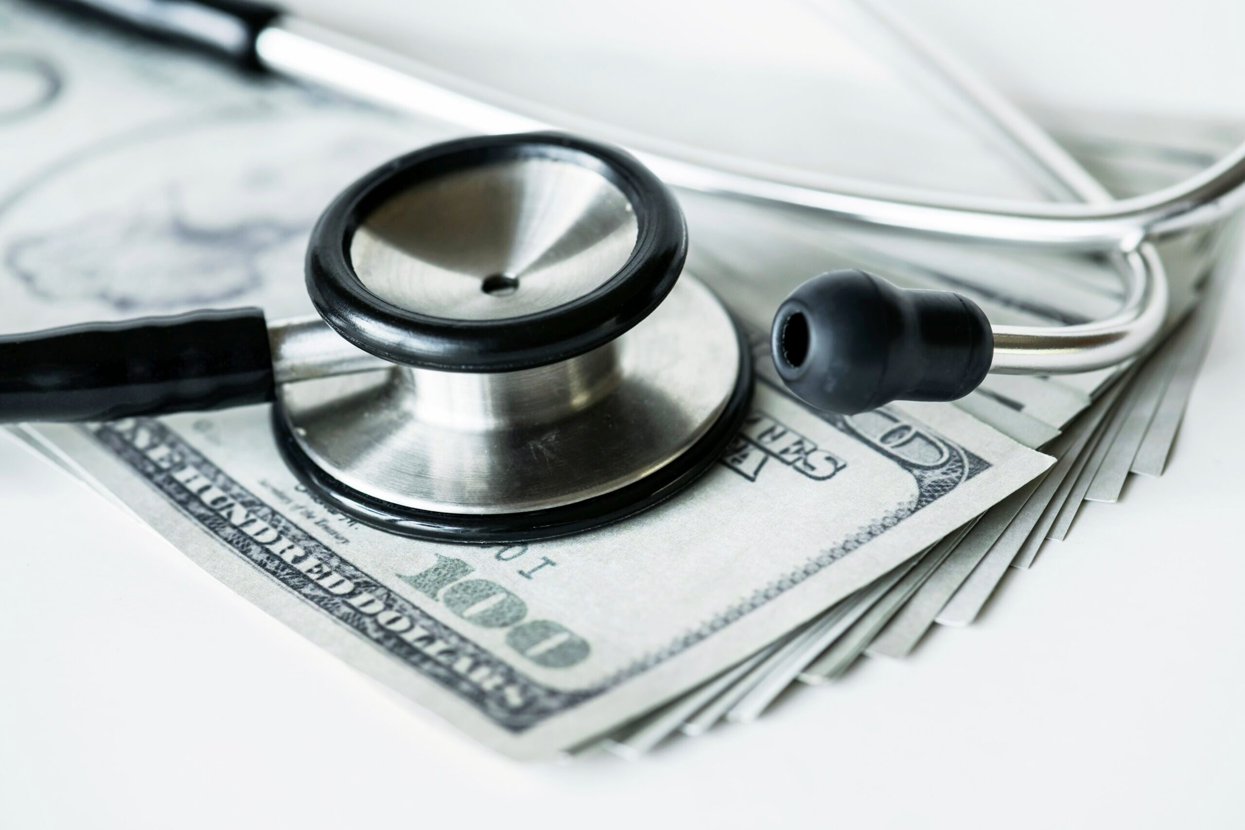 A stethoscope sitting on a pile of money.
