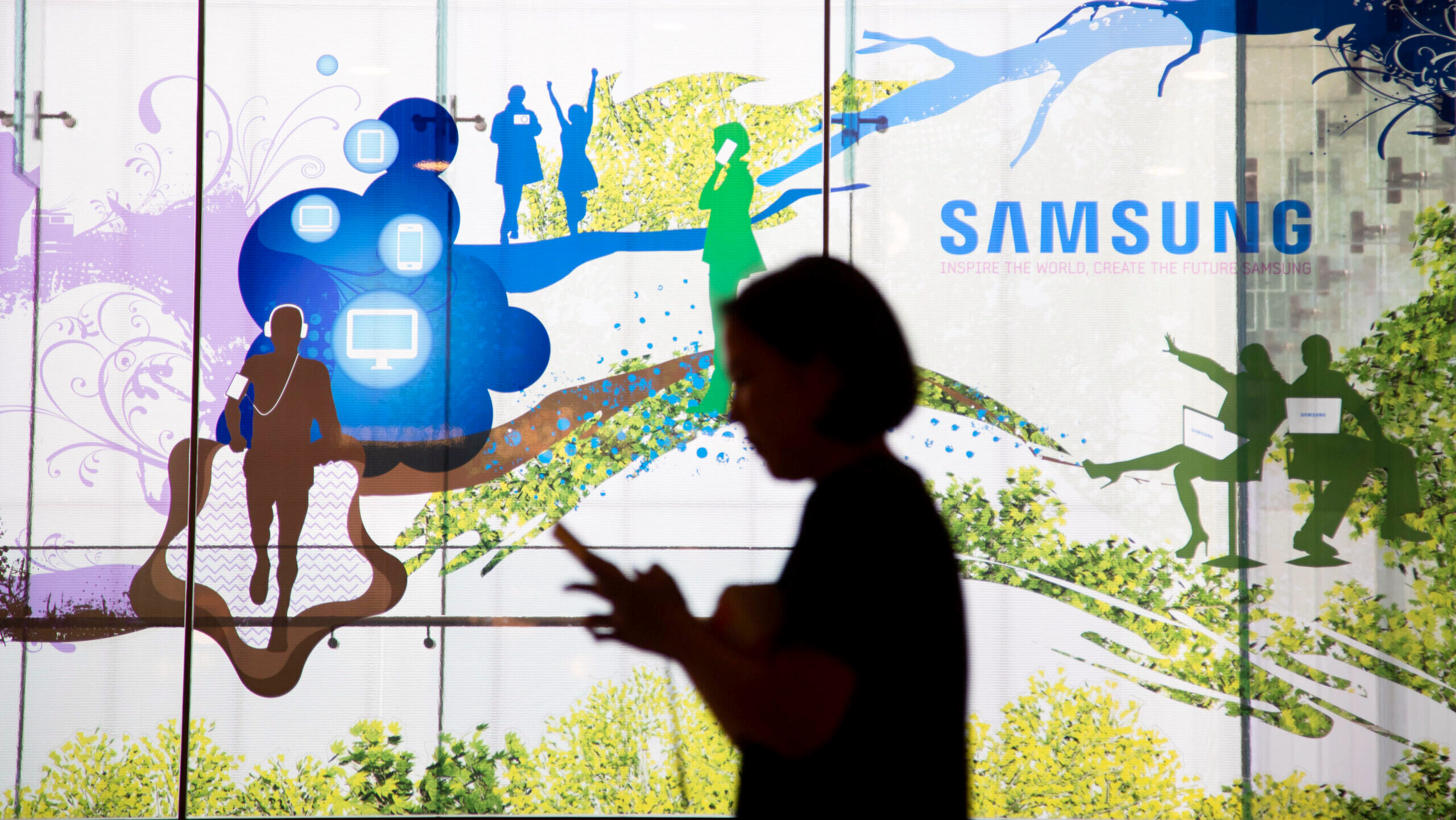 A person, viewed in silhouette, is shown walking inside the Samsung Electronics headquarters in Seoul, South Korea.