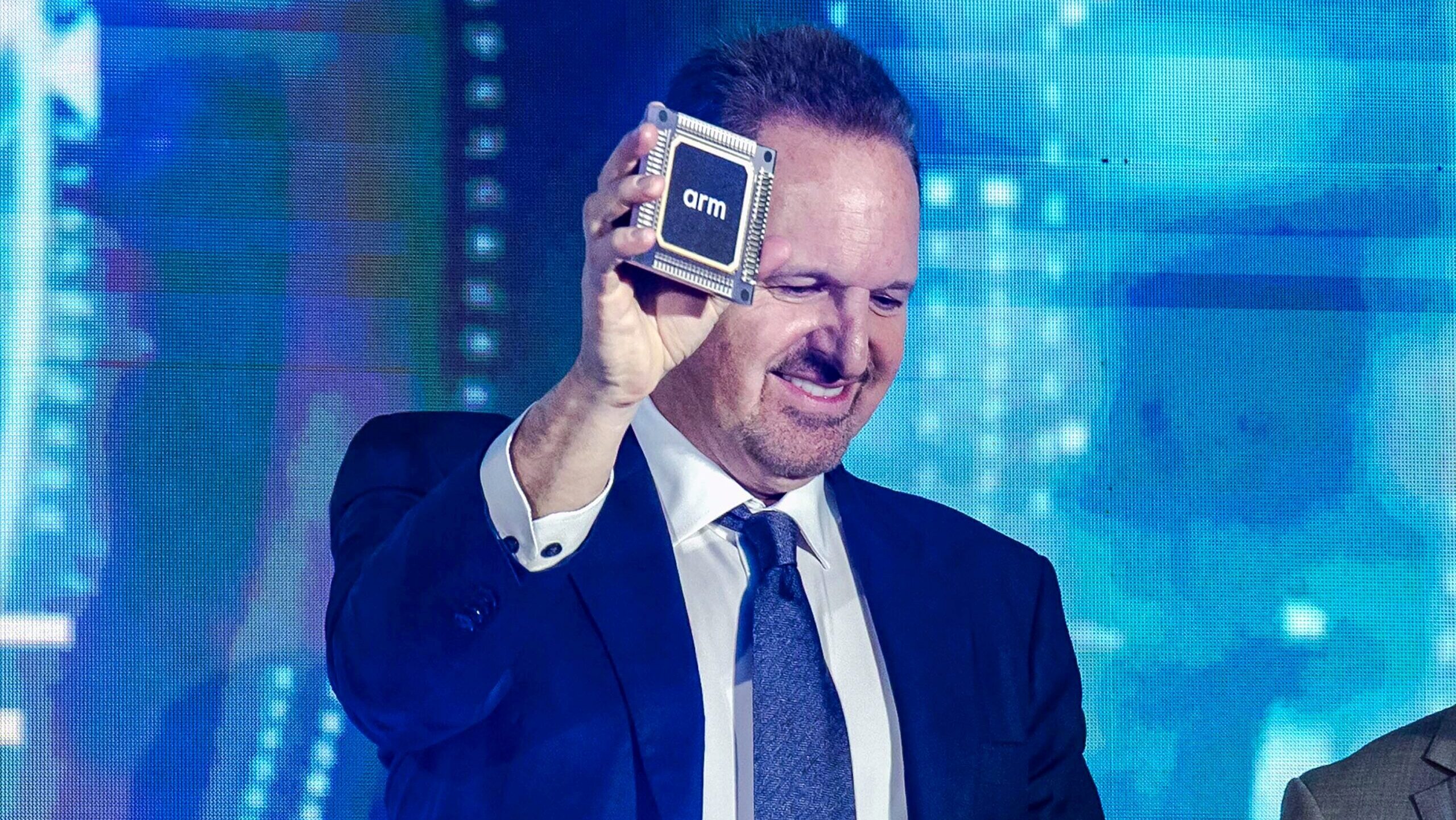 Photo of ARM CEO Rene Haas holding a chip replica at a conference.