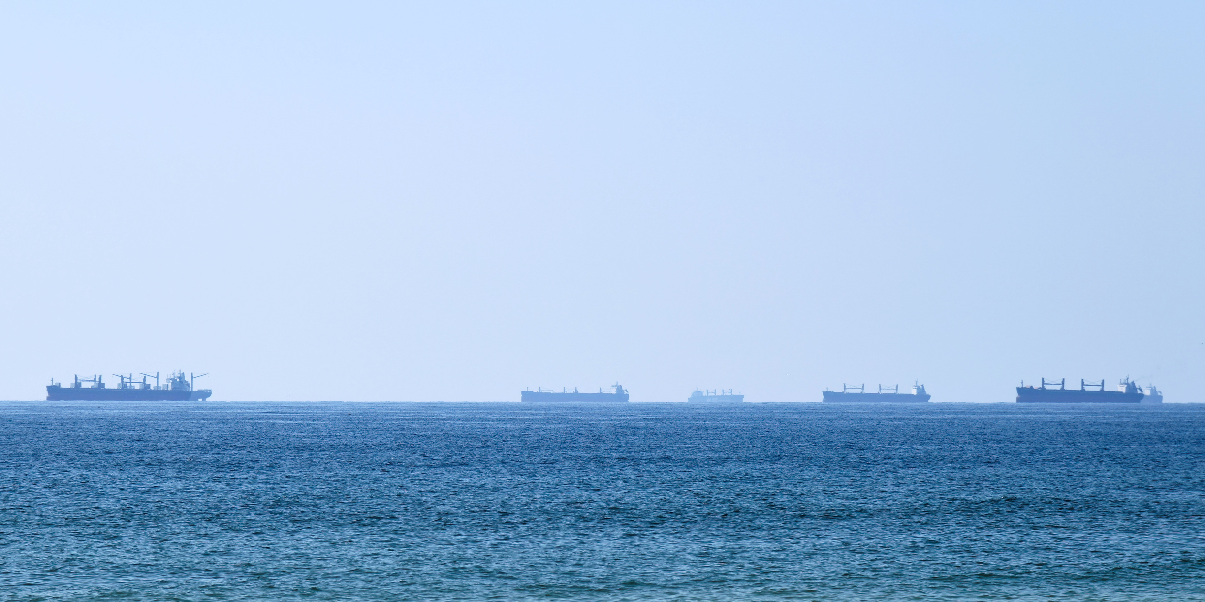 A silhouette of cargo ships line the horizon in Hormuz as seen from Oman.