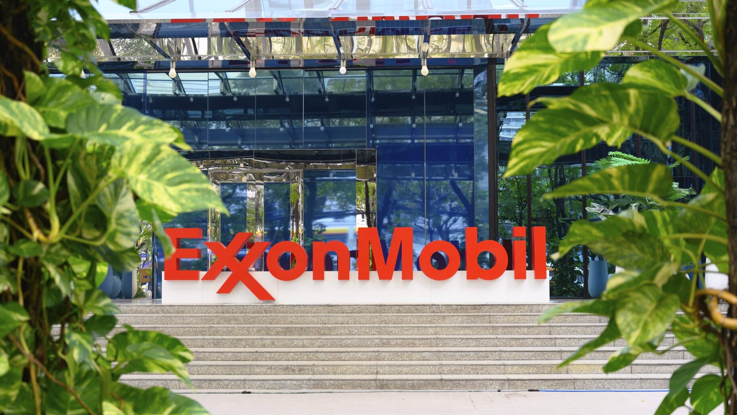 Photo of the Exxon Mobil logo outside an office building entrance.