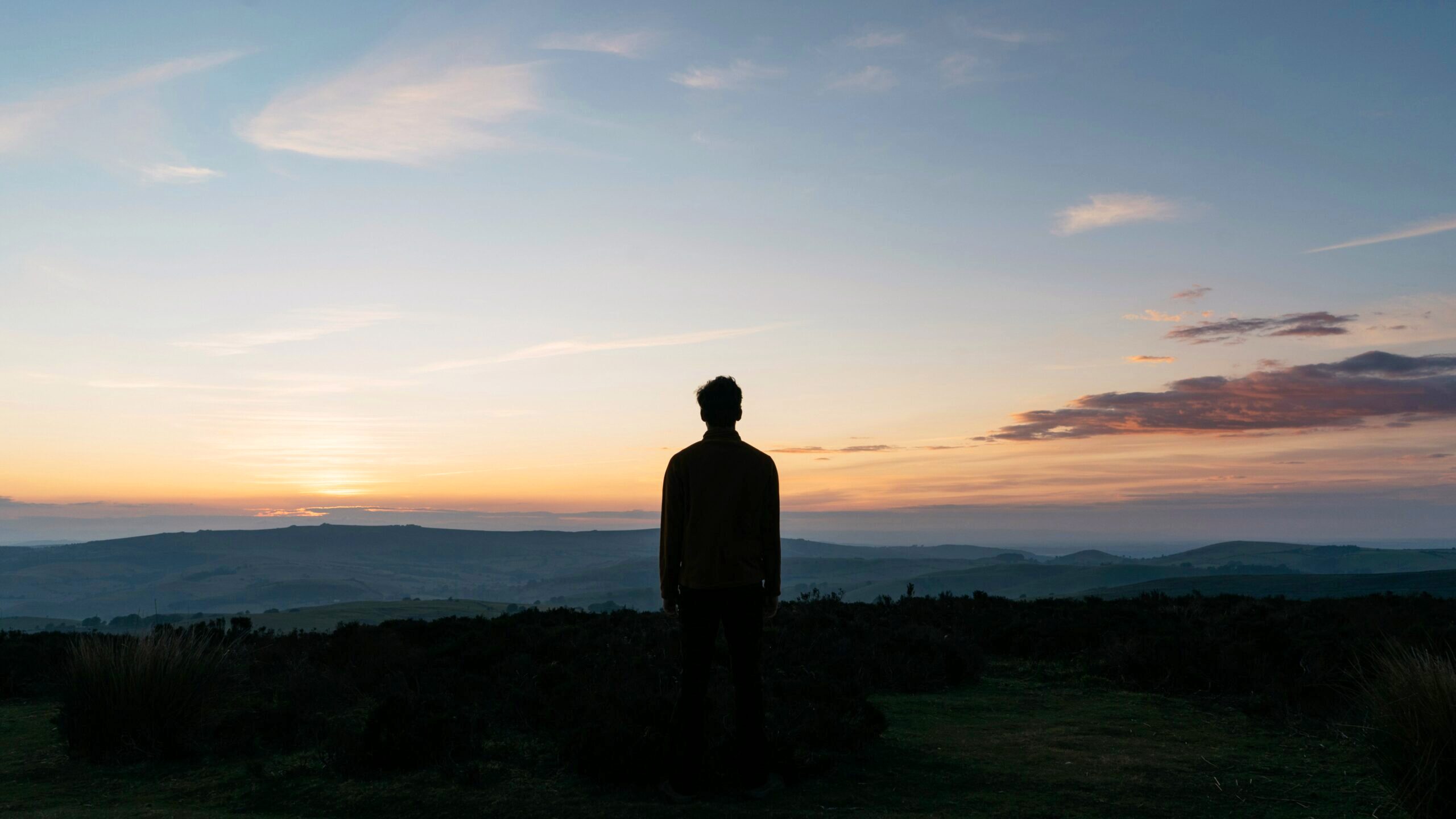 Silhouette of single person standing against a dark background.