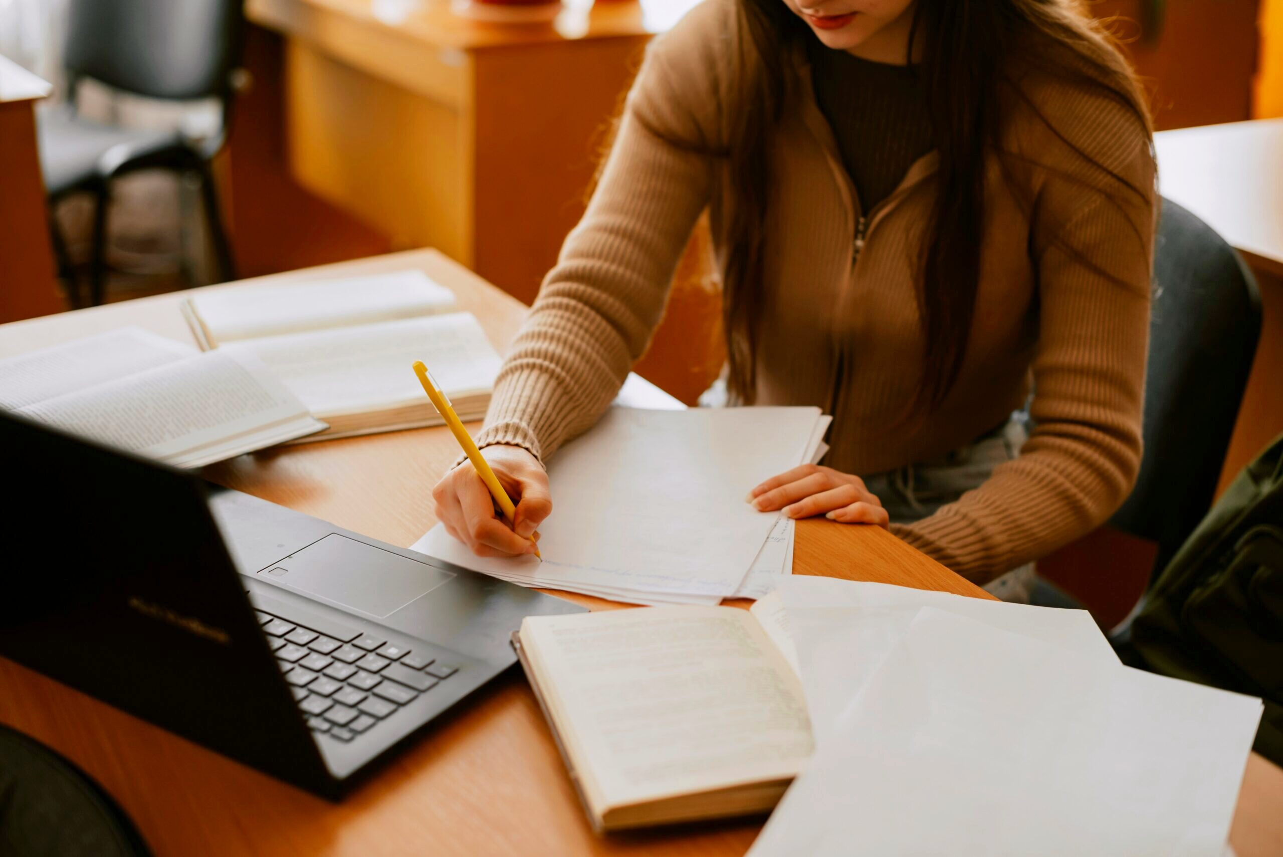 Woman sitting at a desk and writing on paper.