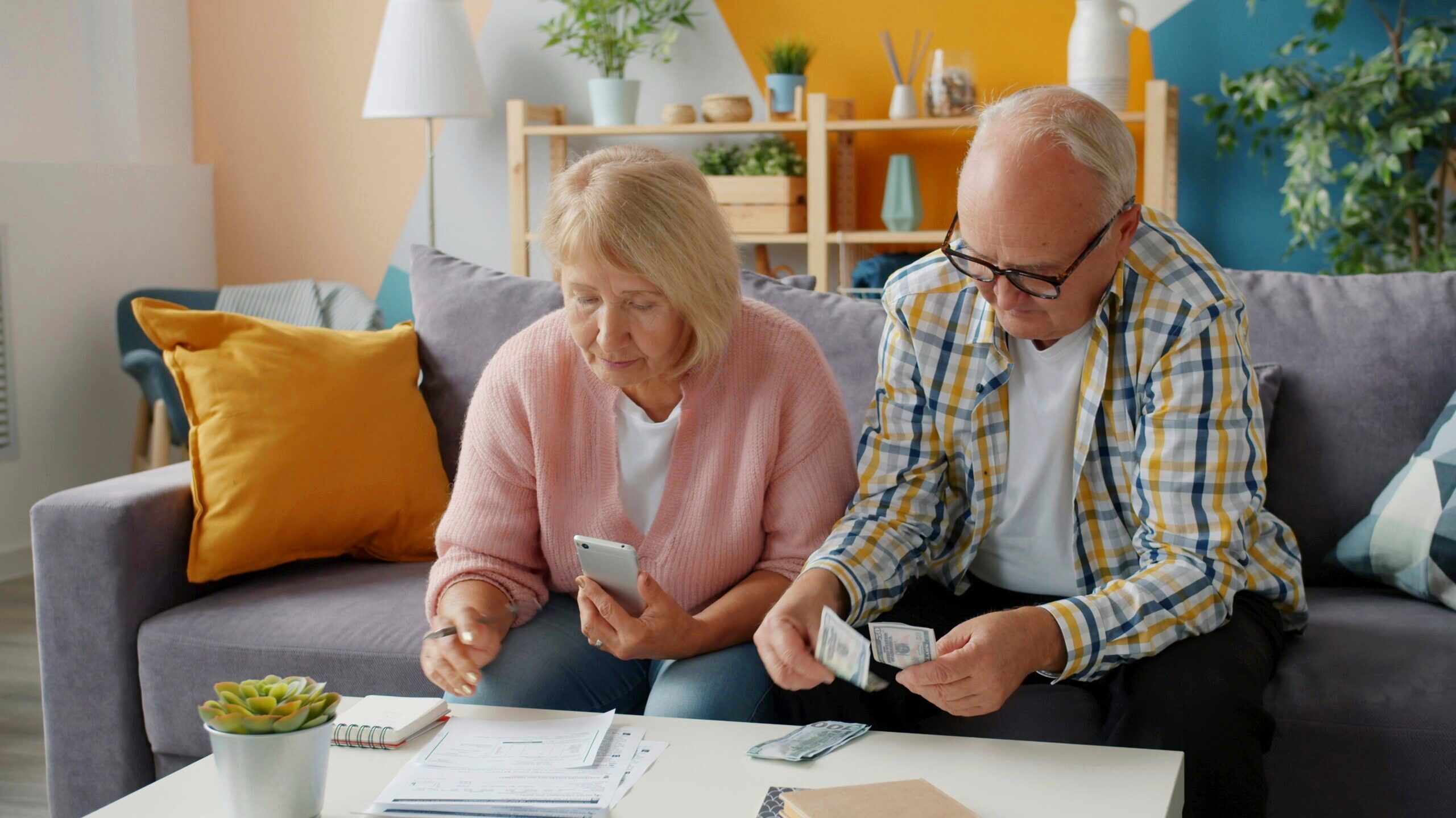 Photo of older couple counting out money and checking documents on a table.