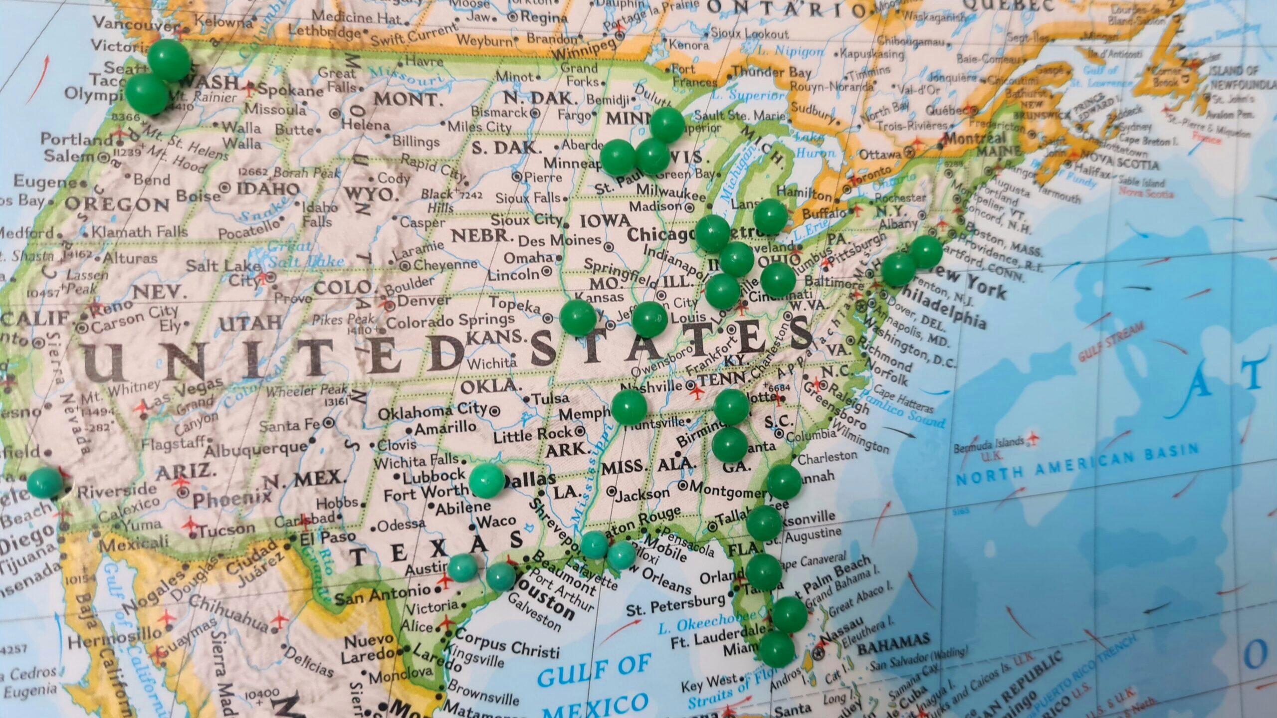 Photo of a map of the United States with several pins placed over cities and states.