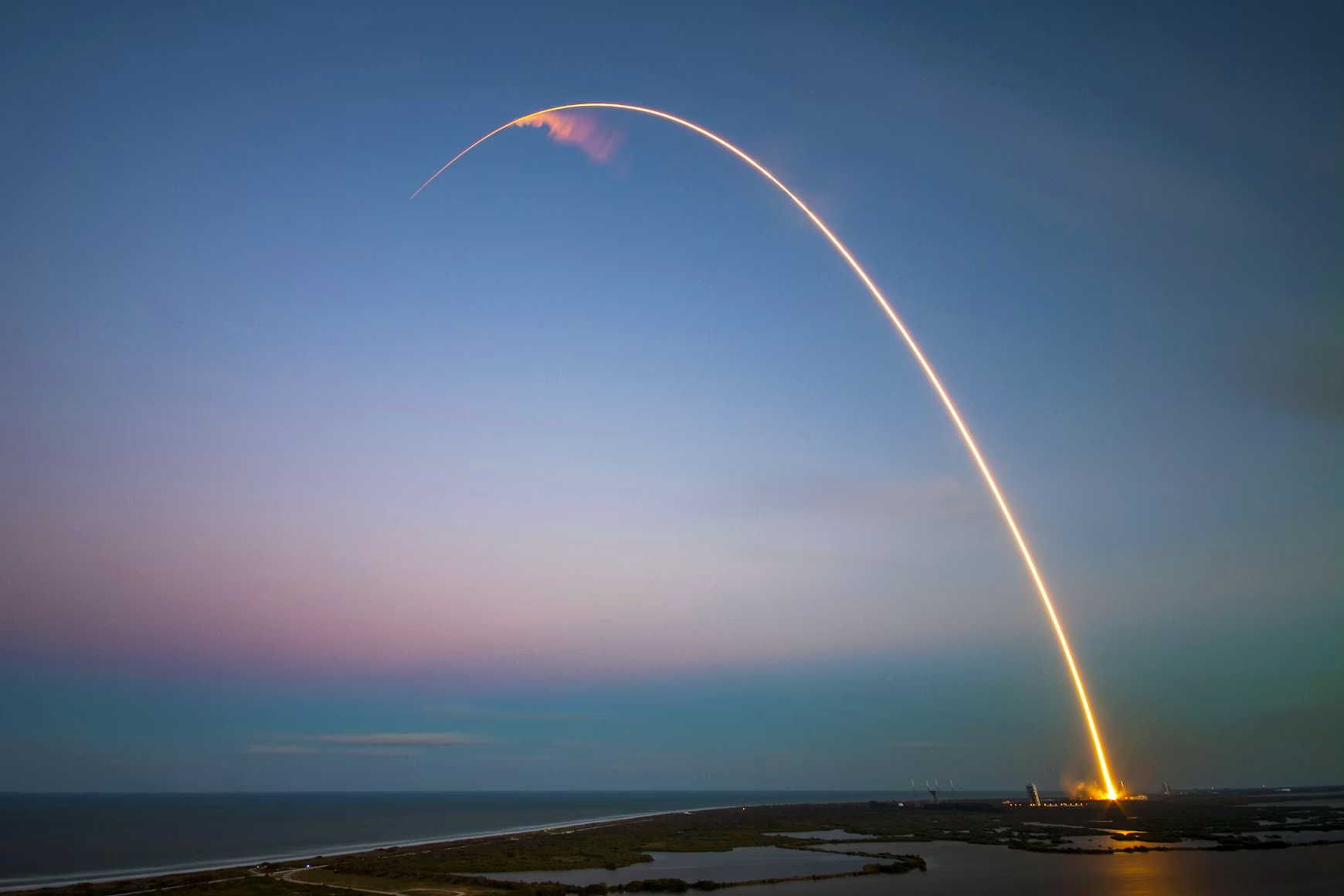 Photo of a rocket ship taking off into a dark blue sky.