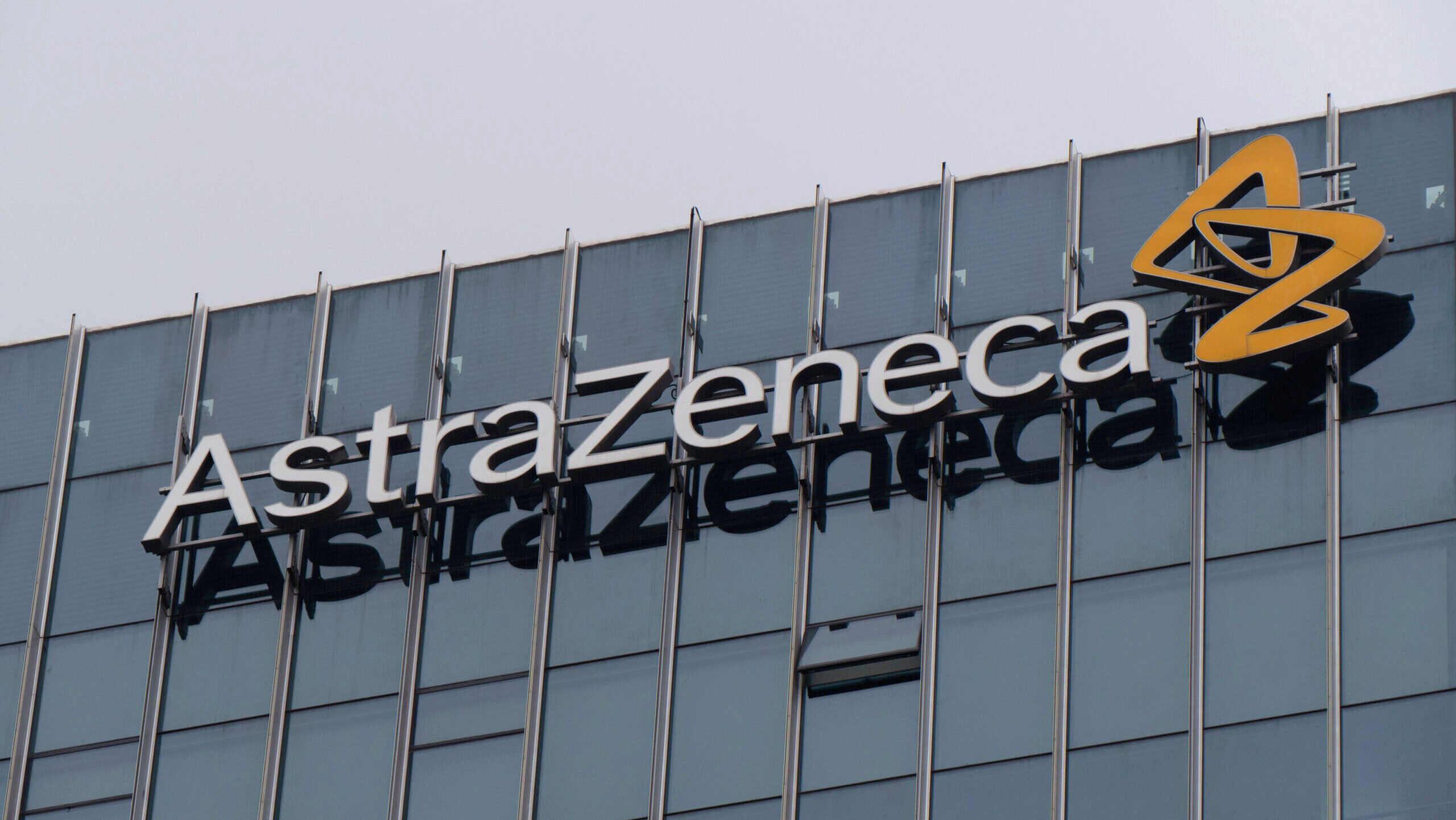 An AstraZeneca office building with the company's lettermark is shown.