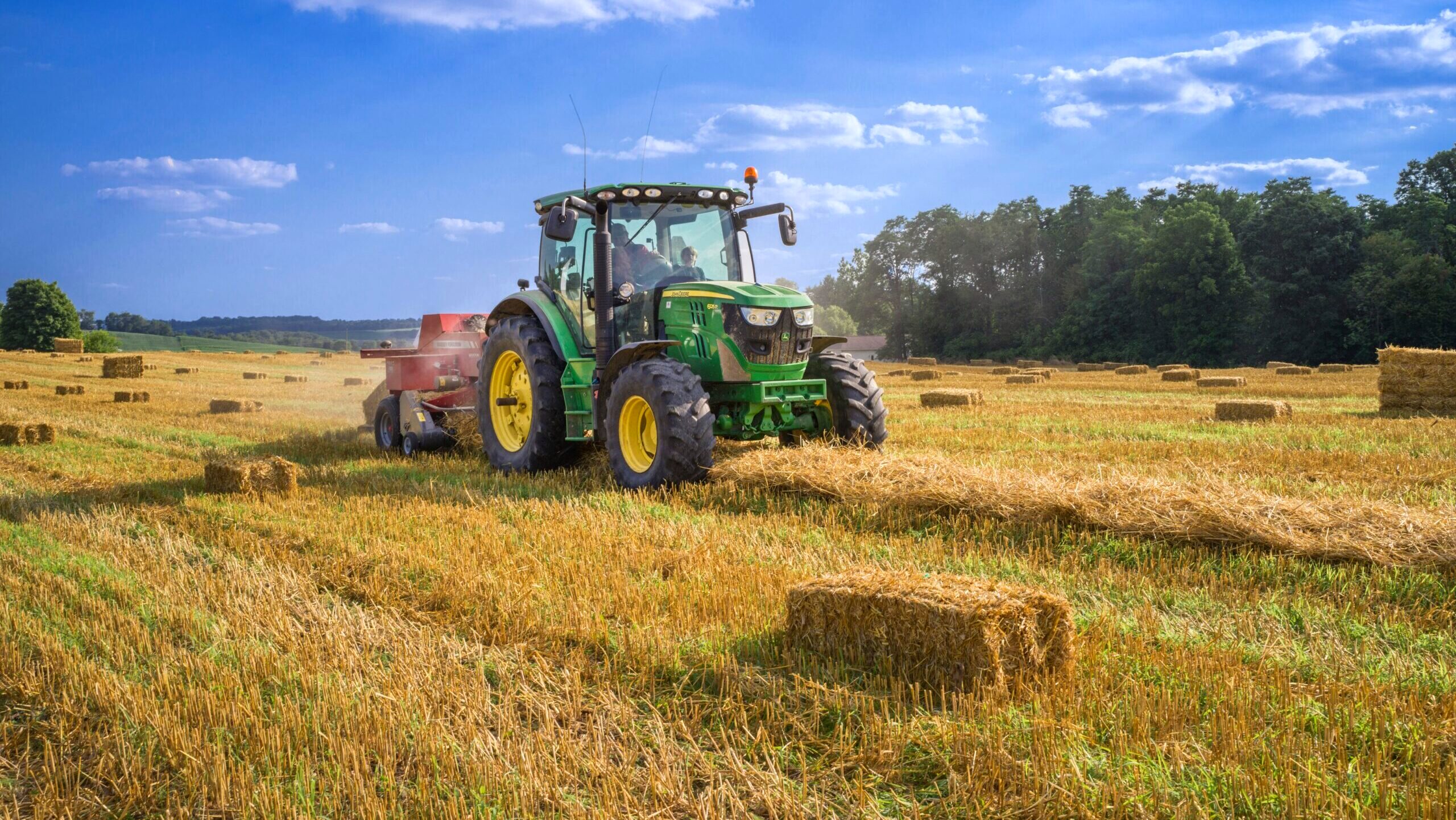 A John Deere tractor is shown working a farm field.