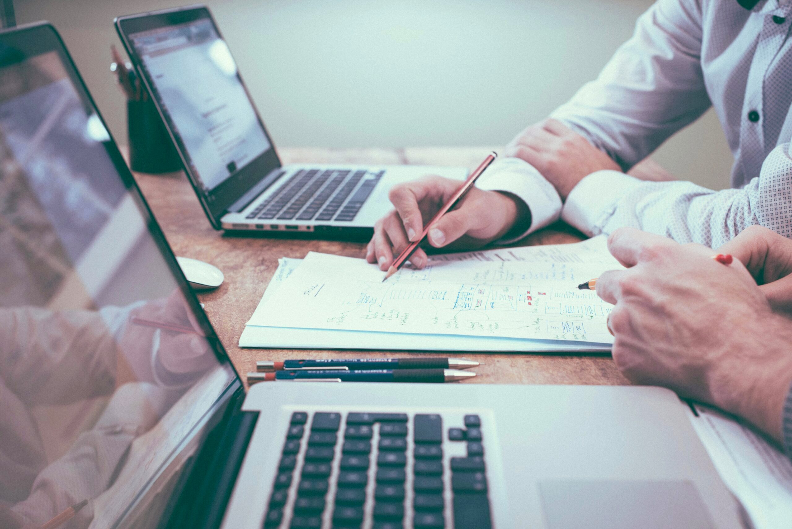 Photo of two people sitting at a desk running calculations on paper.