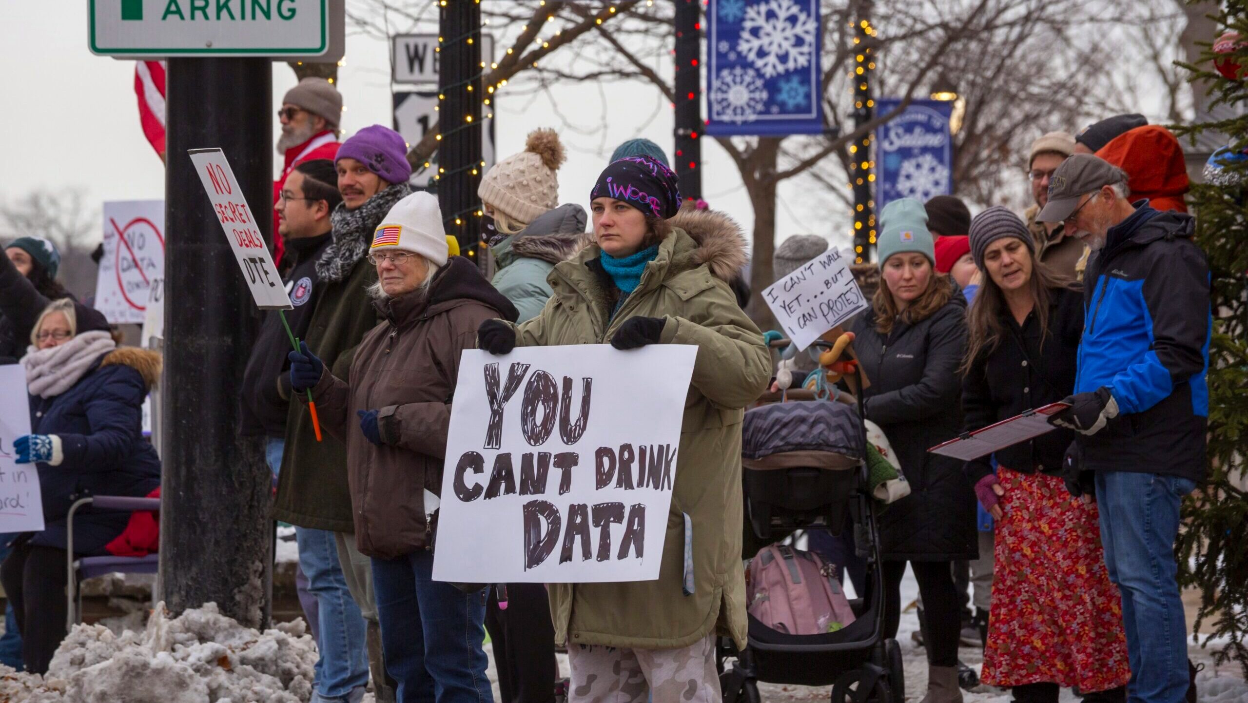 A group of residents in Saline, Michigan hold a protest against data centers on a street corner.